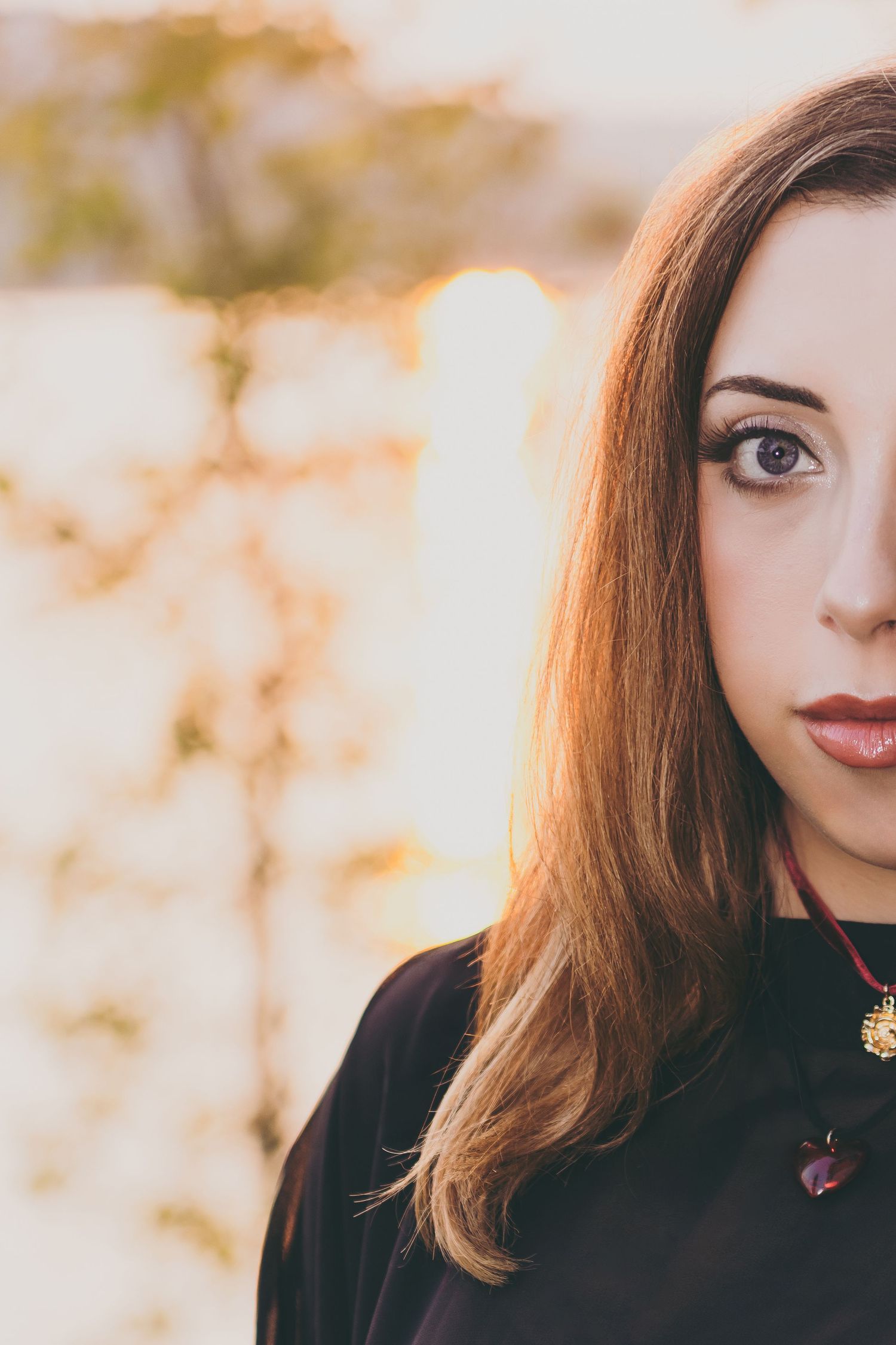 Person wearing black clothing against a soft bokeh background in natural lighting.