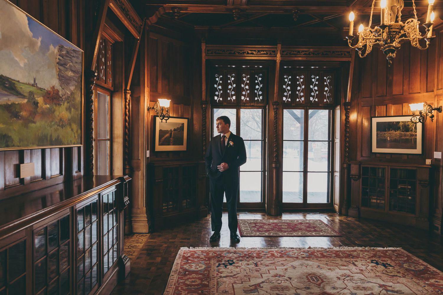 Elegant wood-paneled ballroom with crystal chandeliers and ornate architectural details in warm lighting.