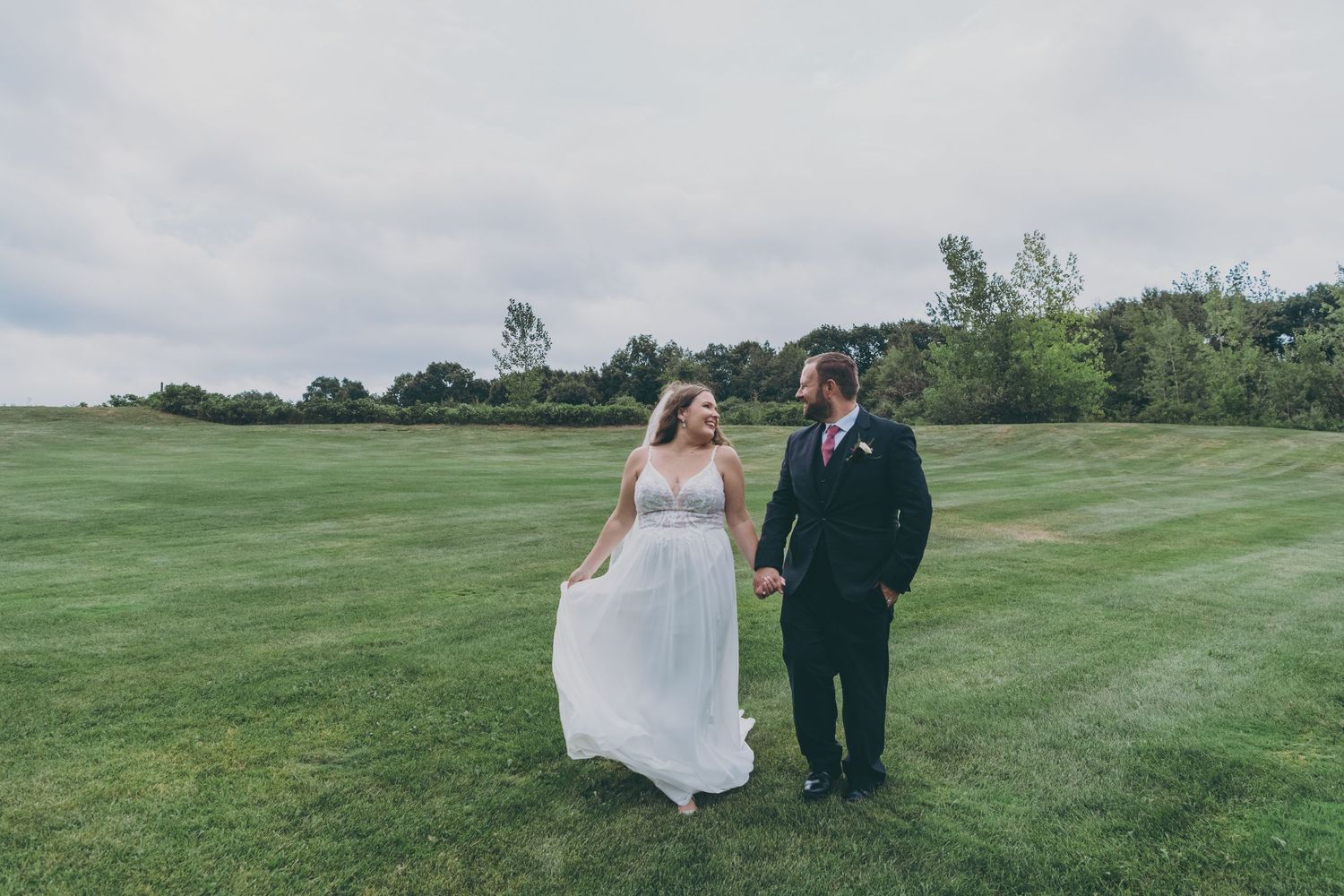 A couple stands together on a lush green golf course during their wedding celebration.