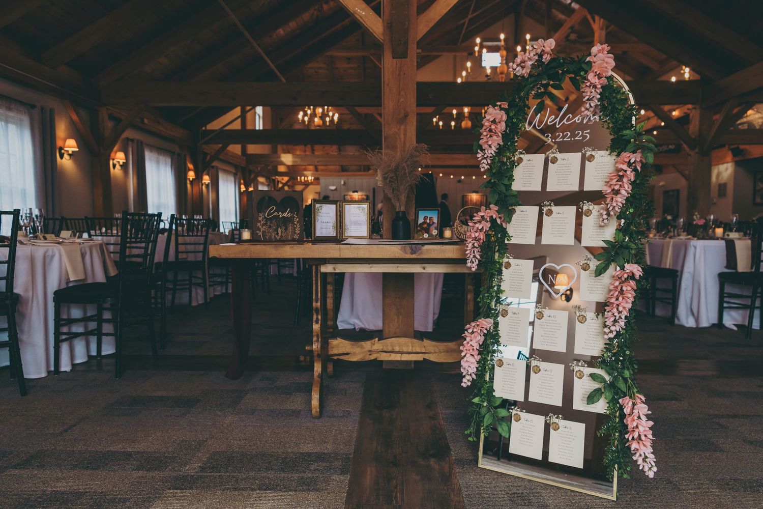 Interior view of an warmly lit empty barn wedding venue with wooden beams and decorative lighting elements.