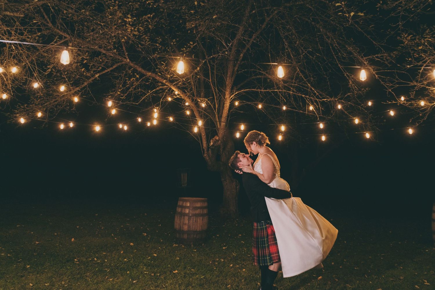 Outdoor wedding reception with string lights creating a romantic ambiance at night.