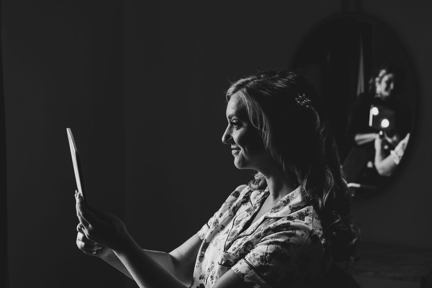 Black and white portrait of performer in floral dress holding a drum stick with dramatic stage lighting from the side at the Granite Rose.