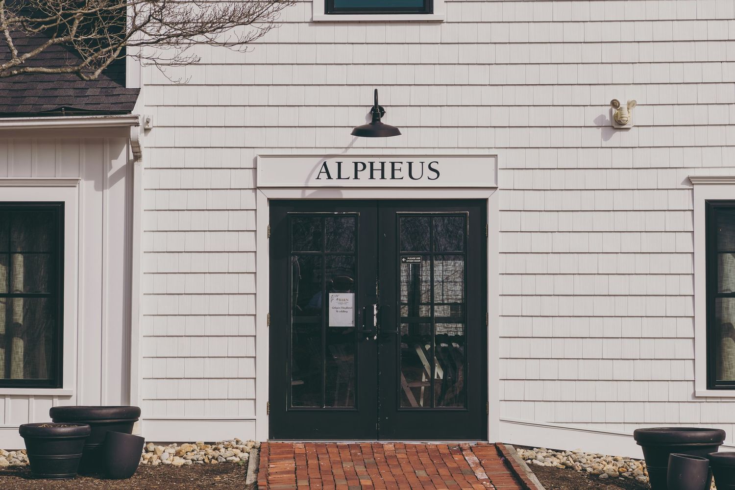 White siding exterior of a small business building with dark green shutters and trim showing historic colonial design.