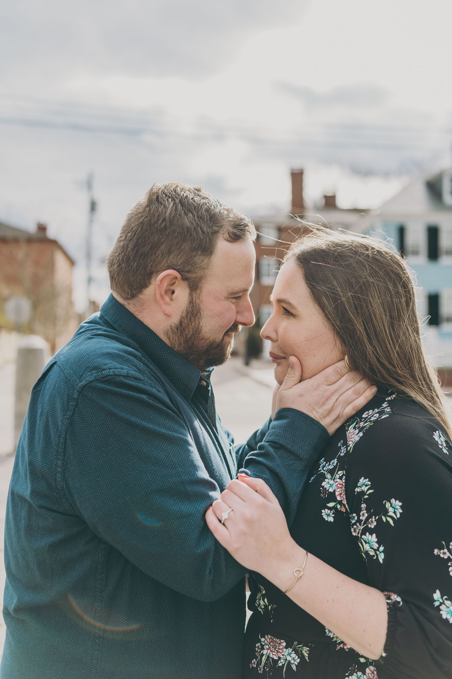 An intimate moment between a couple sharing a tender embrace outdoors on an overcast day.