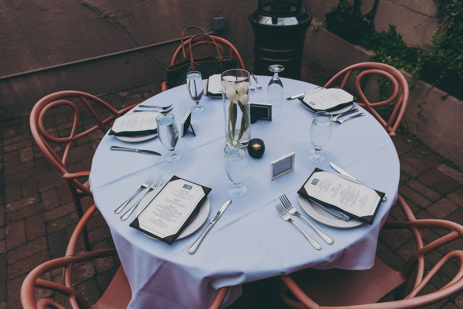 White table settings with wine glasses and cutlery arranged on round tables for an elegant wedding reception.