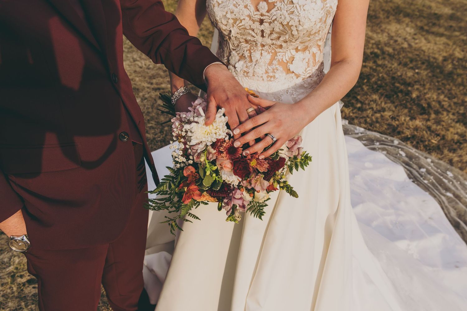 Detail of a white lace wedding dress and colorful bridal bouquet.