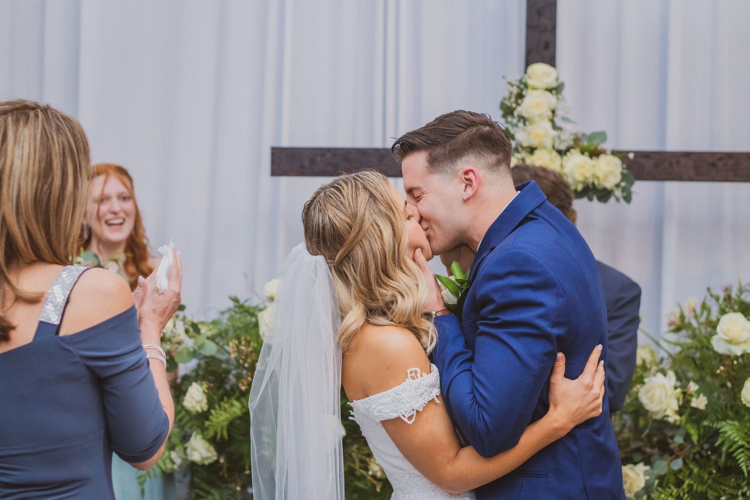 A happy couple hugging and sharing emotional moments during a wedding celebration with floral decorations.