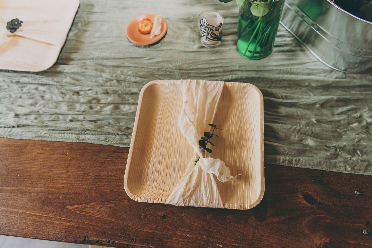Overhead view of wooden serving trays in a warm rustic setting with glasses and tableware.