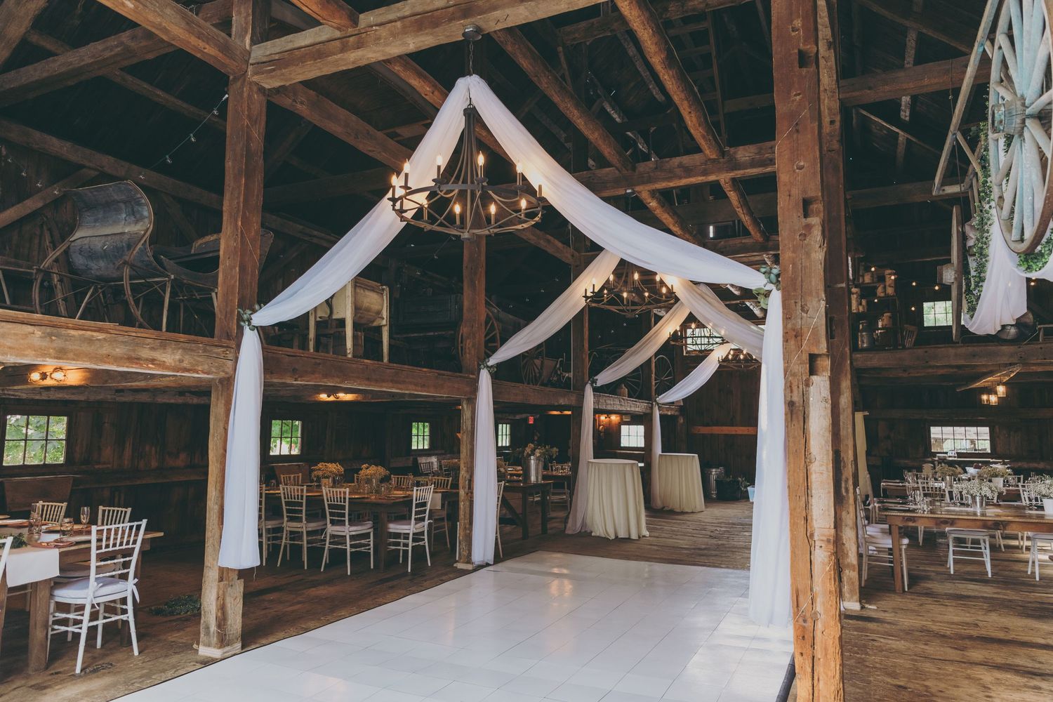 Barn wedding venue interior with white fabric draping and exposed wooden beams.
