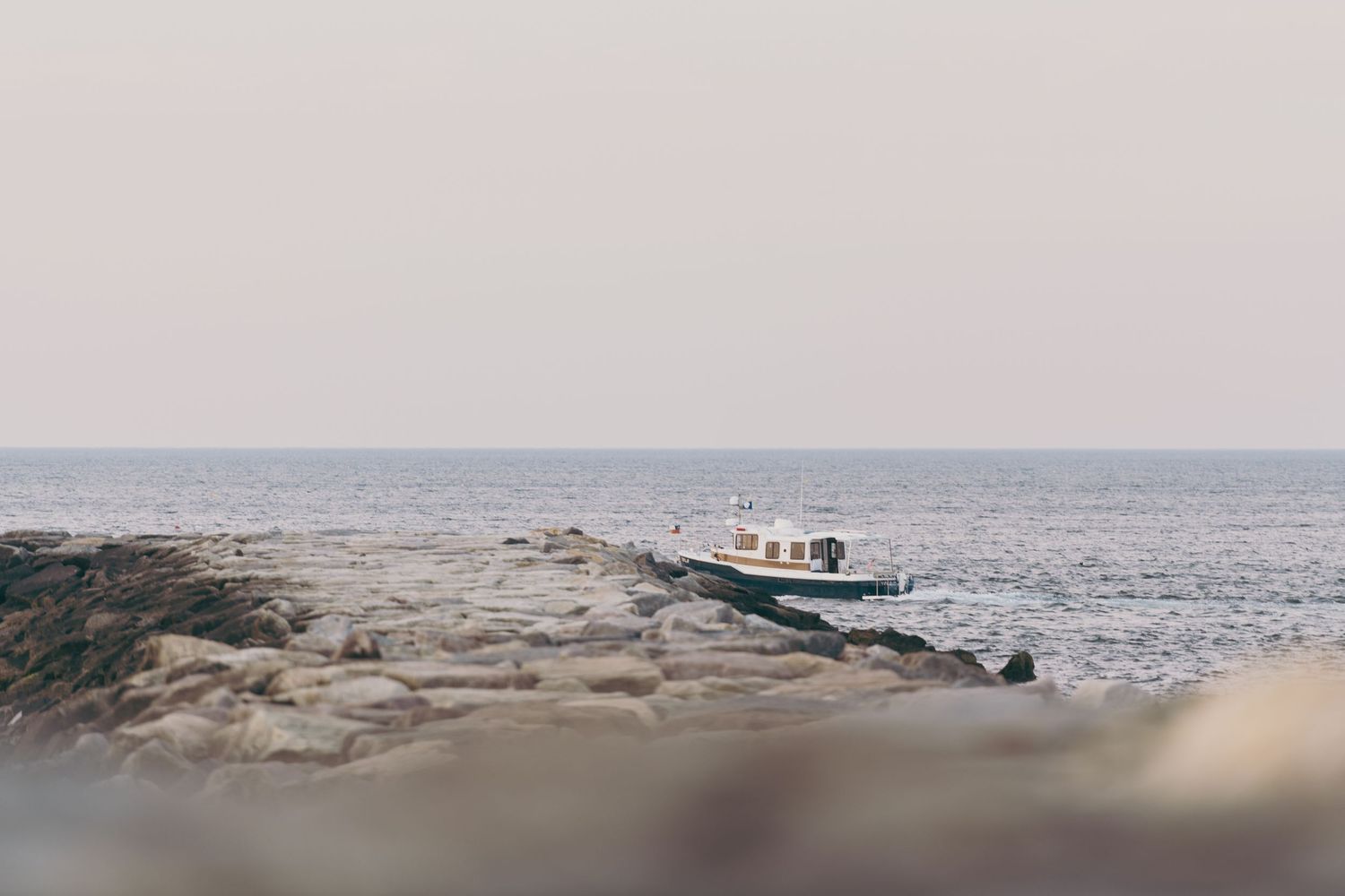 A panoramic collage of coastal scenes showing rocky beaches, boats, and ocean views in cool blue tones.