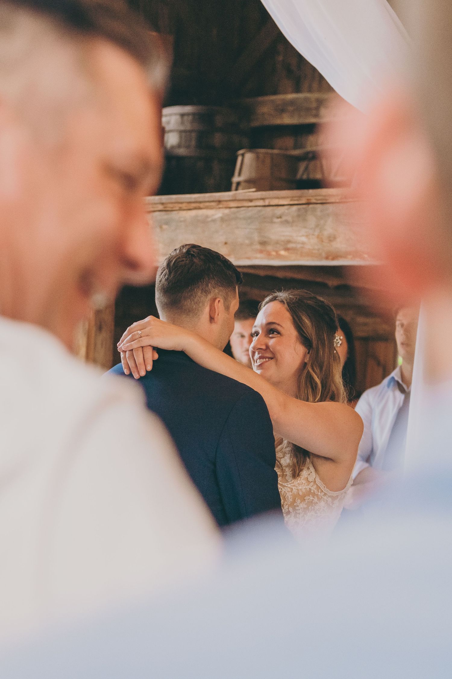 Joyful wedding celebration captured through guests with couple dancing in soft focus.