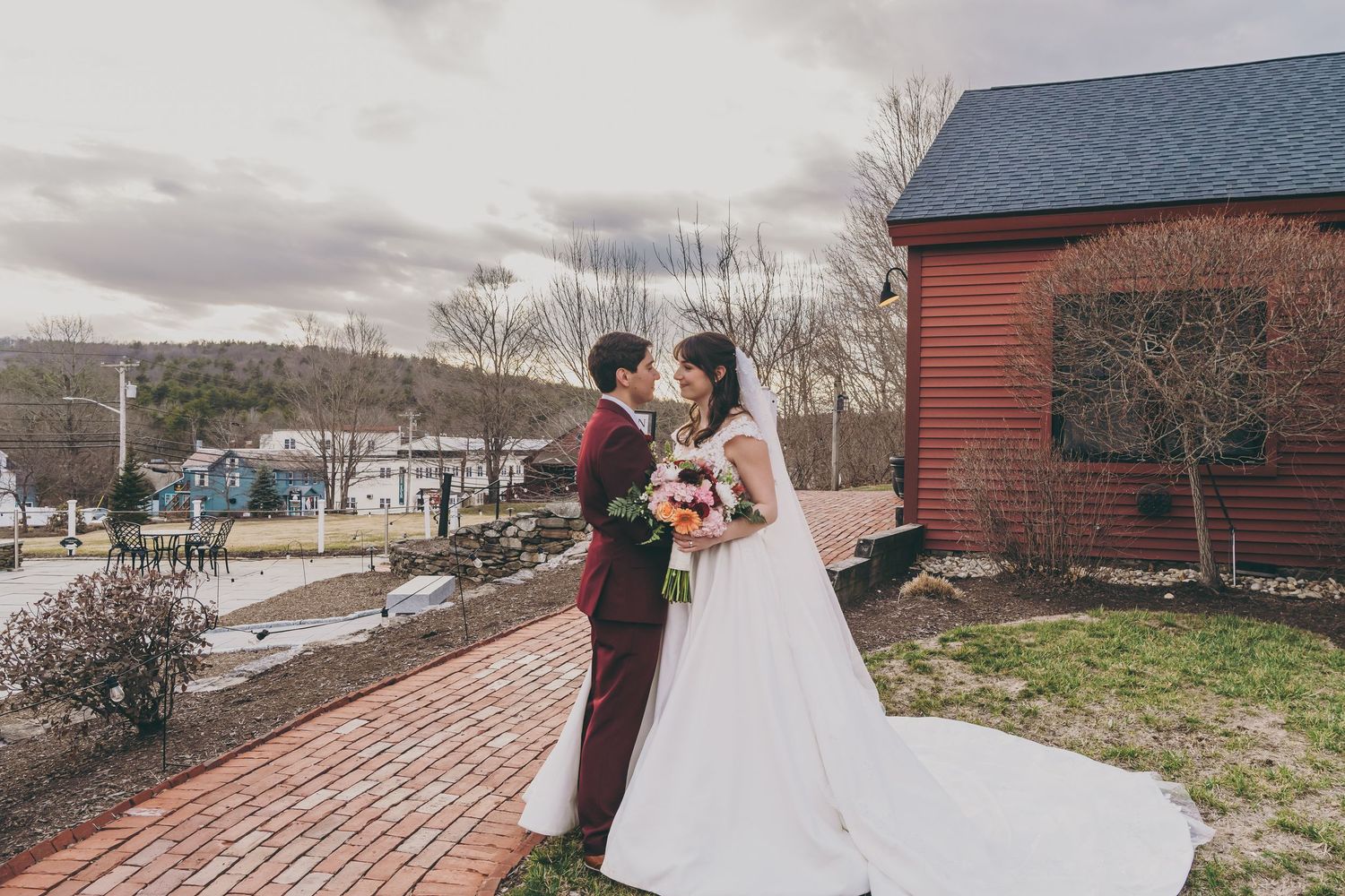 Outdoor winter wedding ceremony with snow-covered grounds and buildings visible in the background.