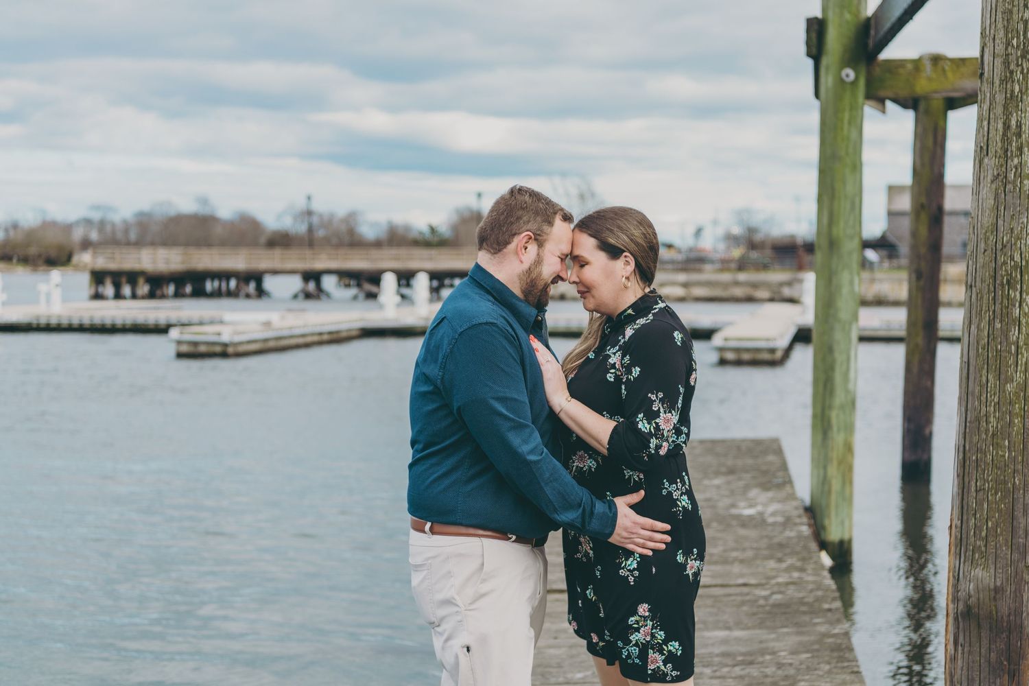 A couple embraces on a wooden dock by the water during a romantic sunset moment.