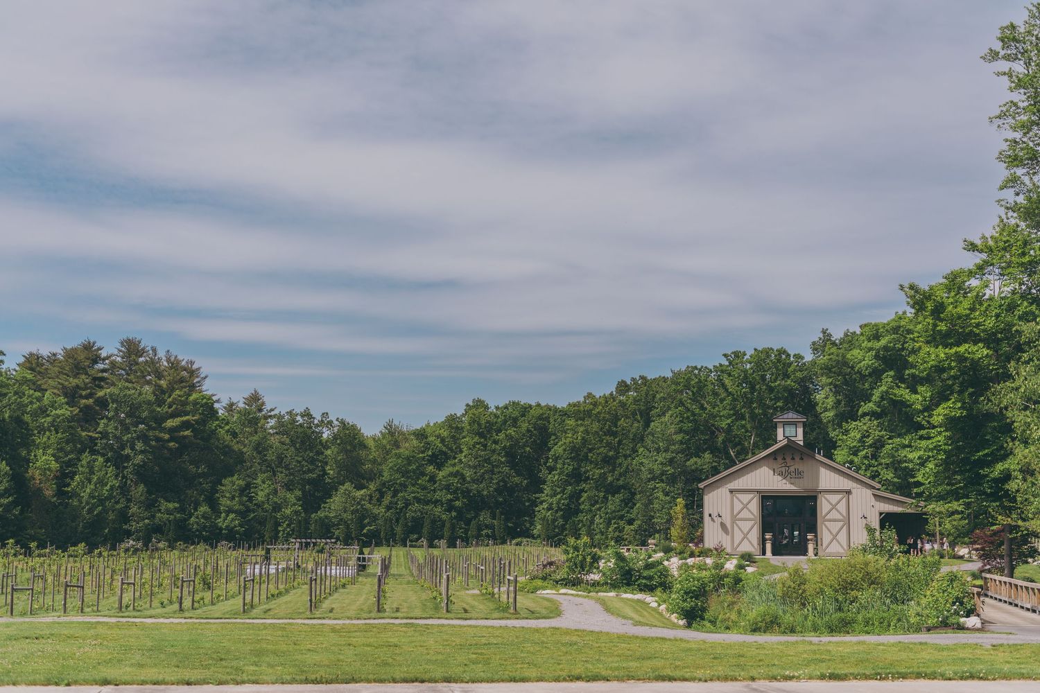 Scenic aerial view of a rustic barn venue nestled among rolling hills and tree-lined fields.