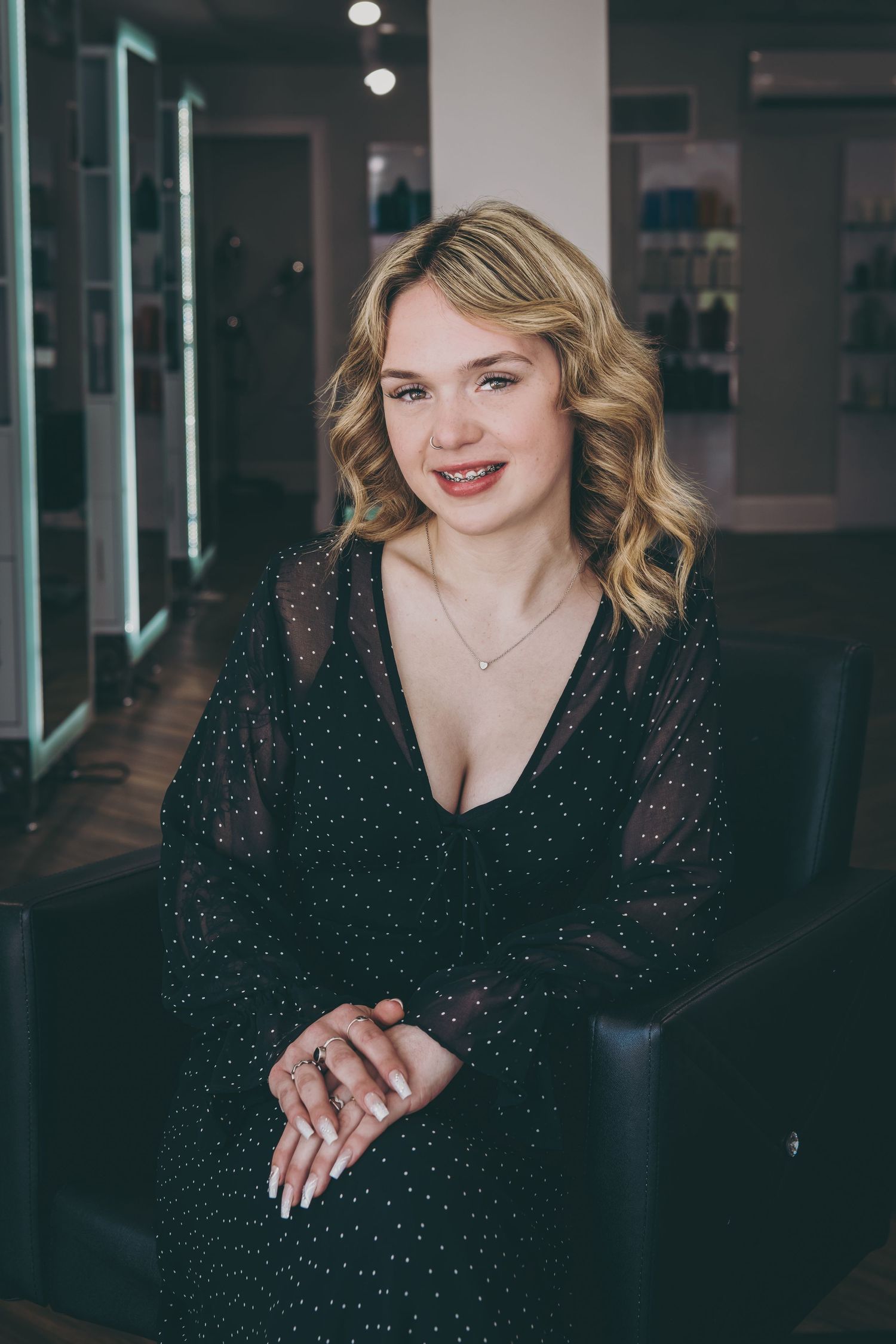 Portrait of woman in sparkly black dress seated in modern studio setting.
