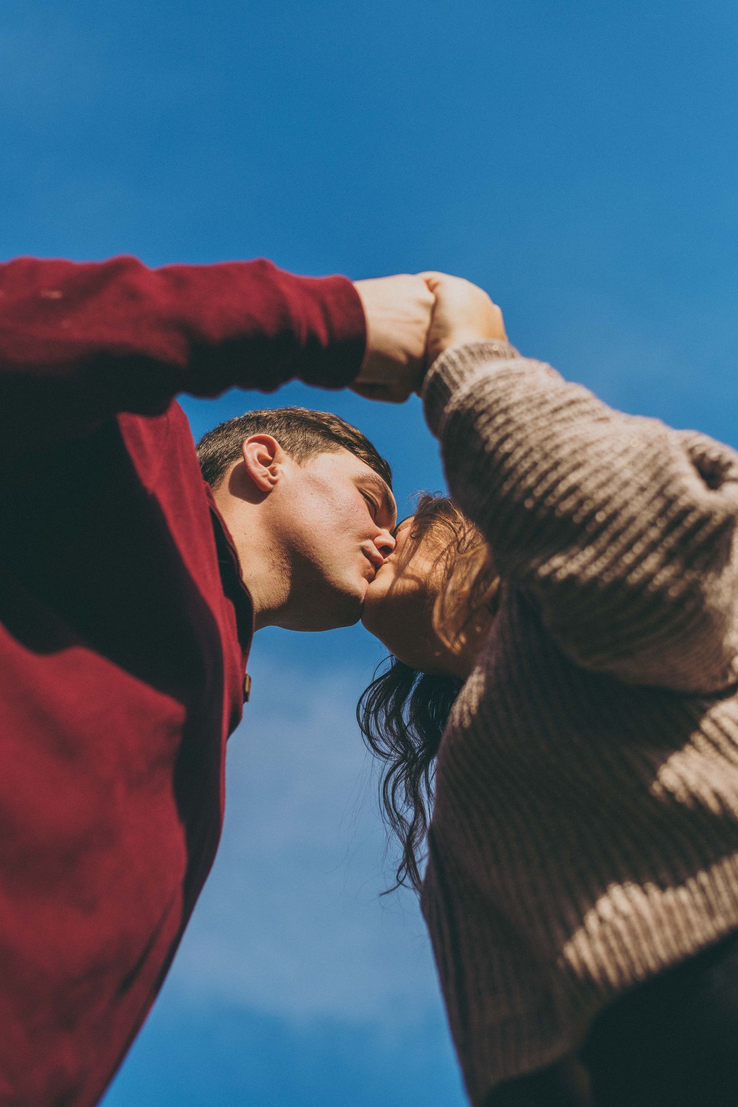 Artistic low angle shots of couple against vibrant blue sky.