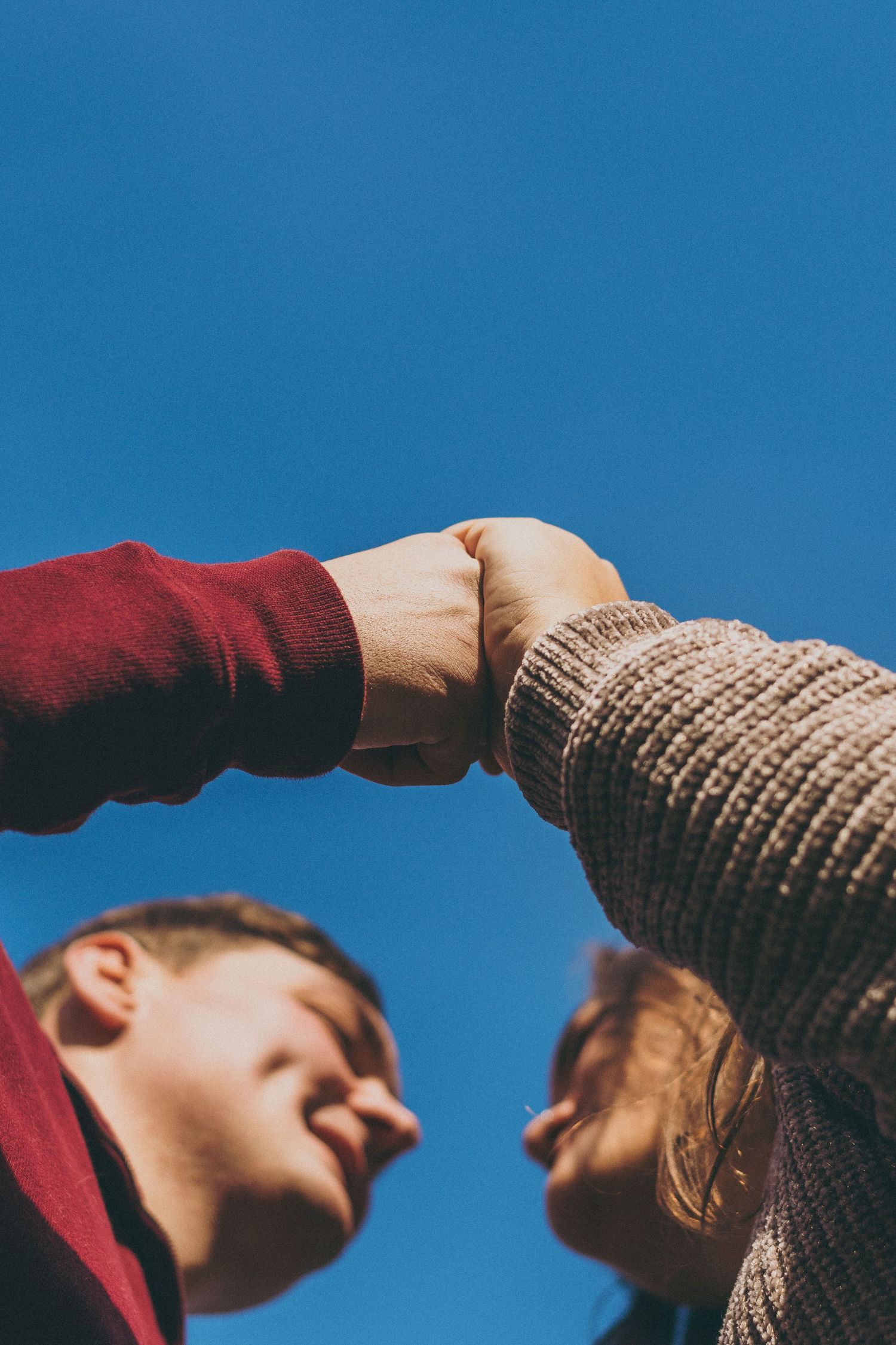 Low angle shot against blue sky of couple in winter wear sharing an intimate moment.
