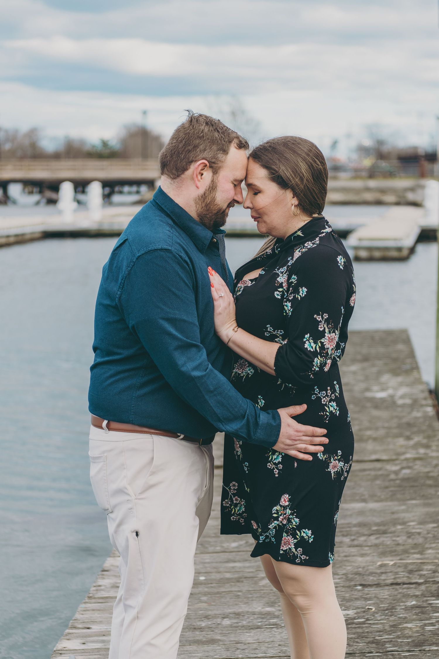 Romantic waterfront engagement session with ocean and pier in background.