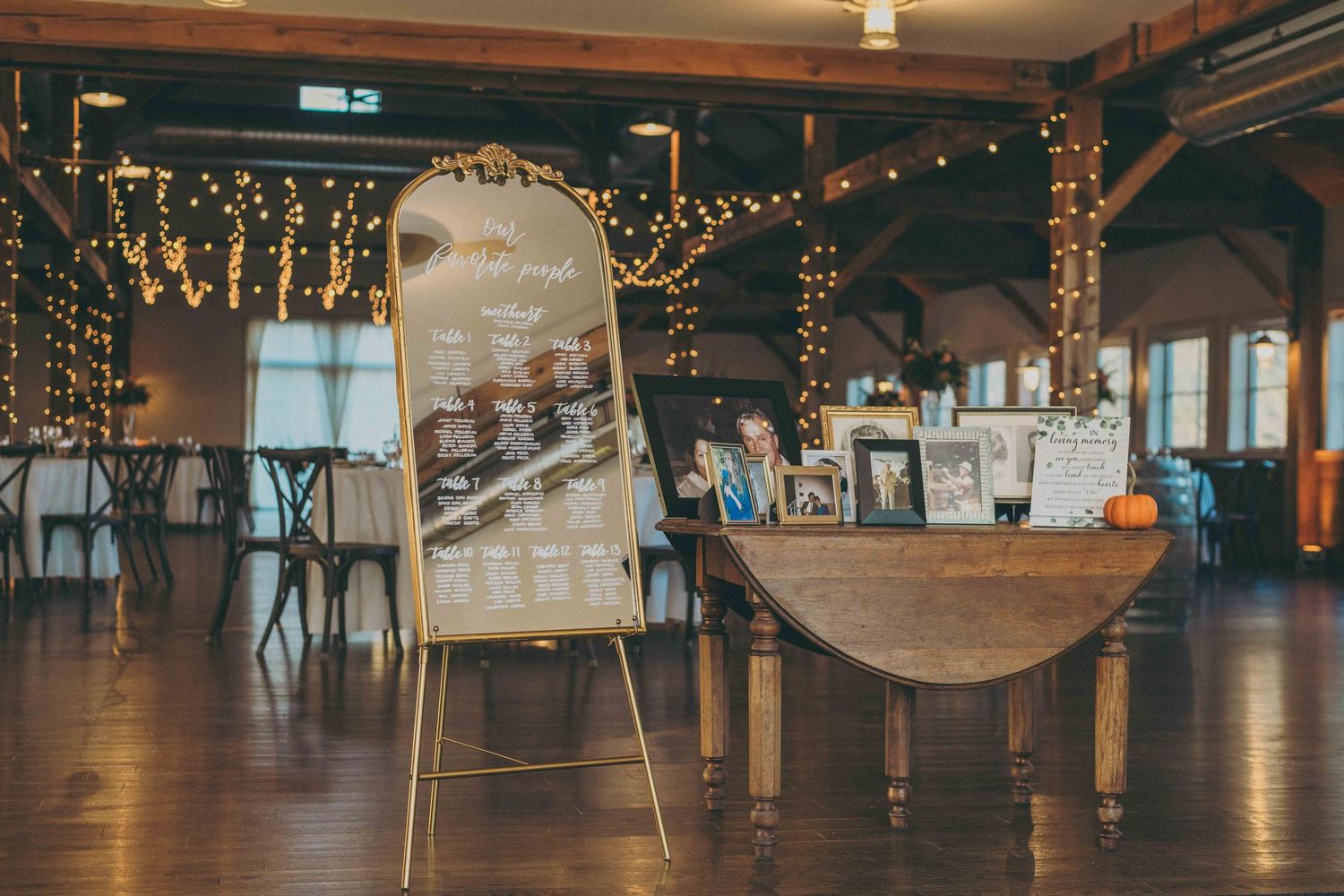 A rustic indoor event venue with wooden beams and twinkling string lights creating a warm, romantic atmosphere.