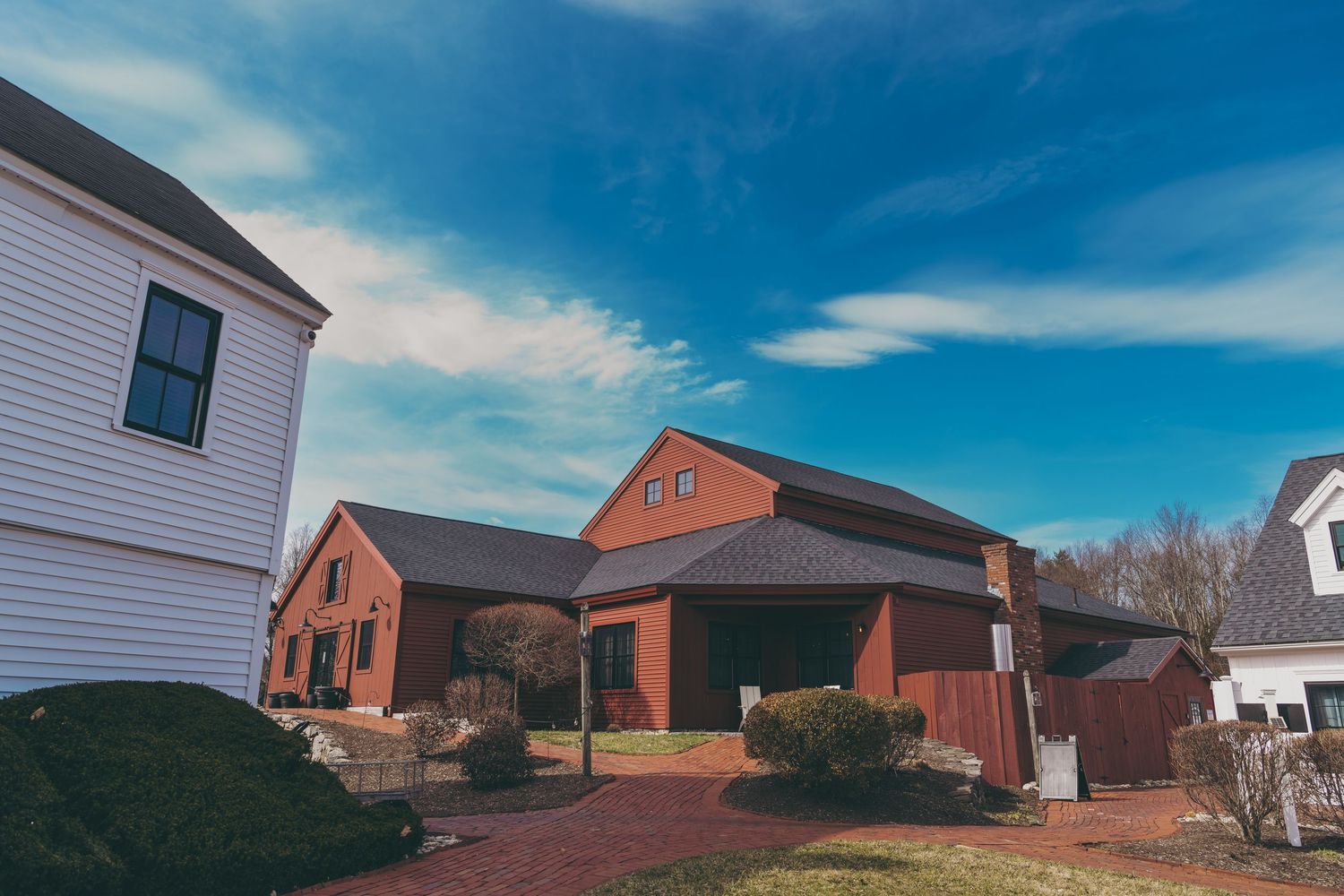 Residential neighborhood exterior view with white and red brick houses against vibrant blue sky on a sunny day.