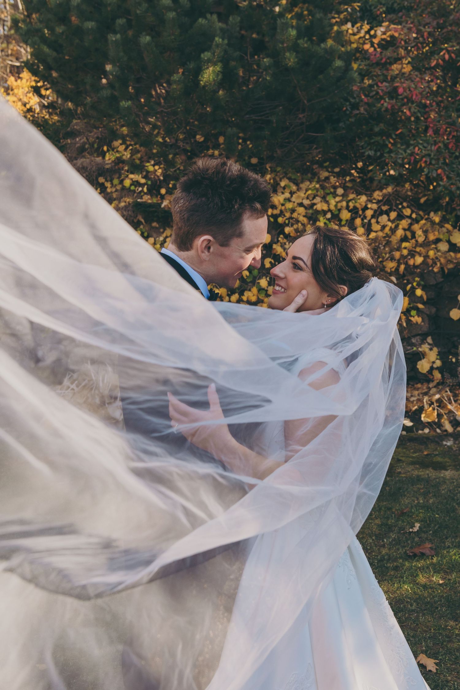 Long white veil flowing elegantly in the wind during an outdoor autumn wedding photoshoot.