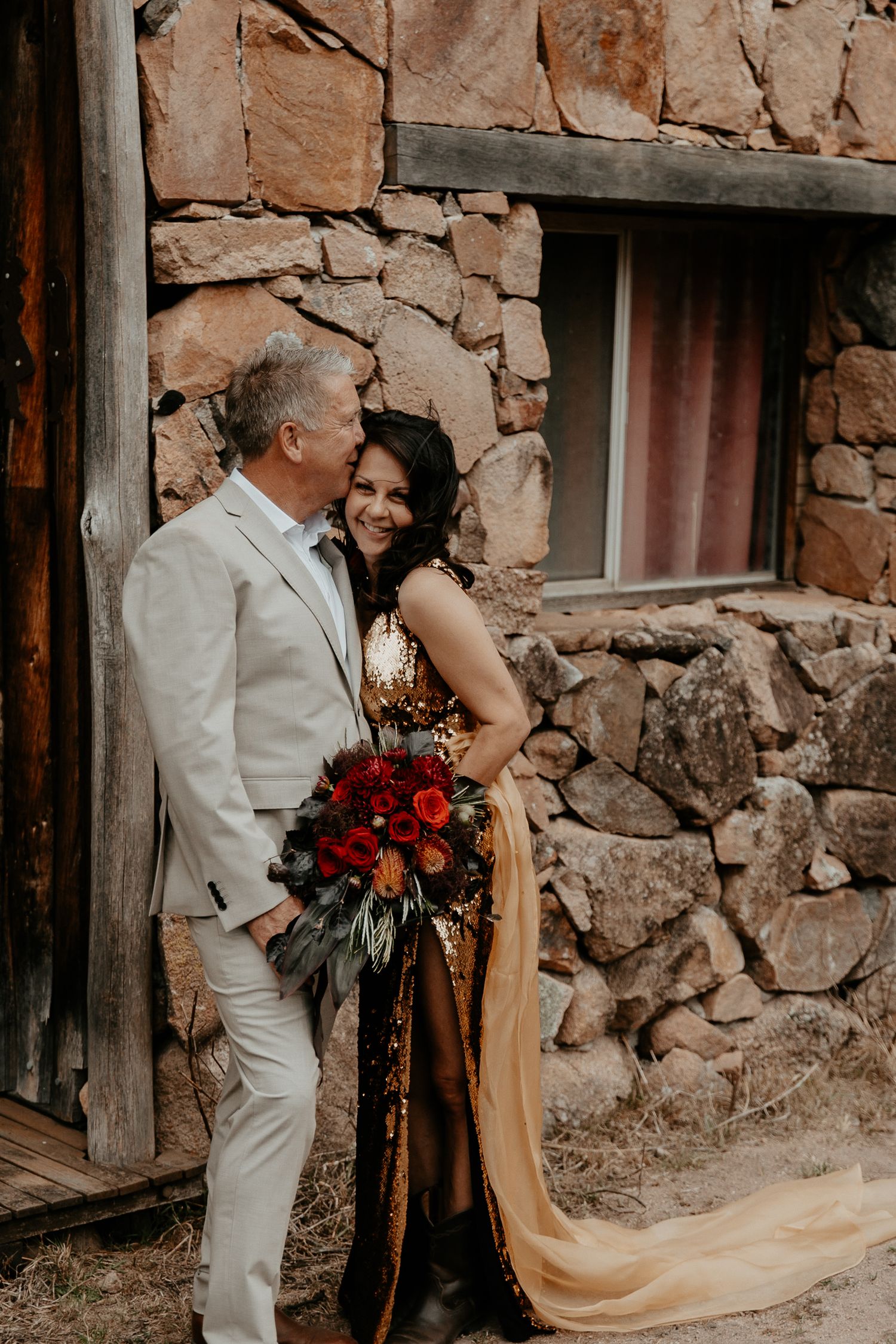 A country style wedding photo of the bride and groom embracing near the old stone cottage.