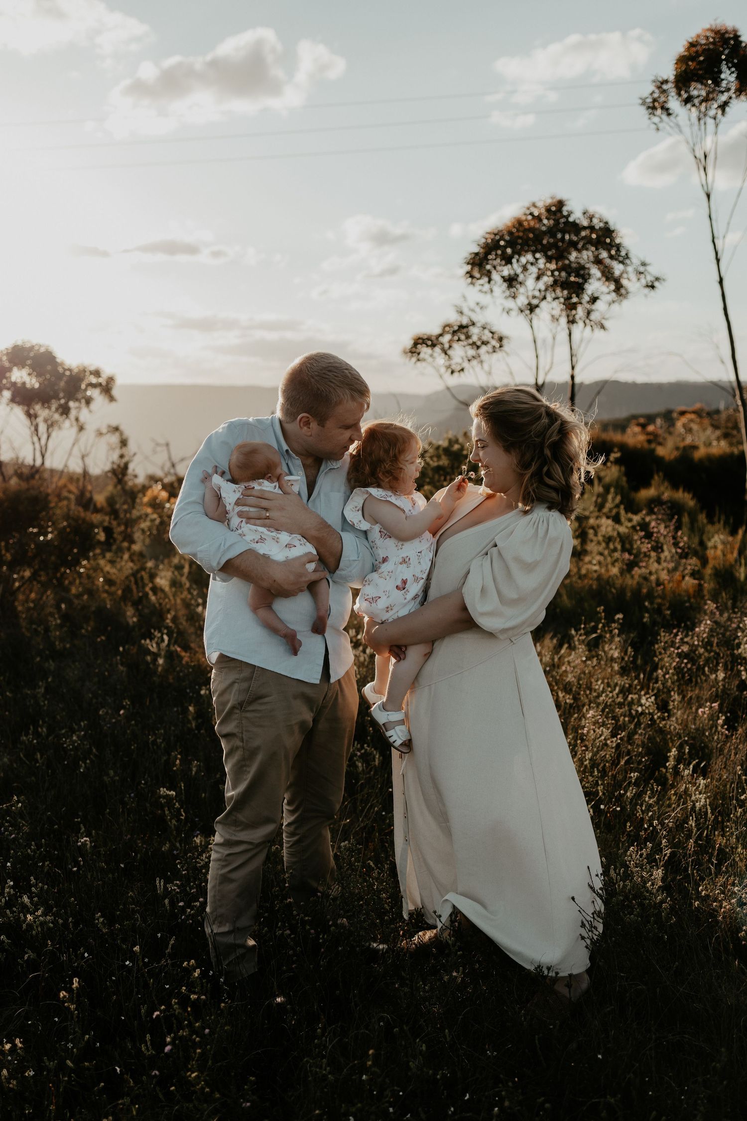 A family of four pictured with the parents holding their children in the golden light in the Blue Mountains