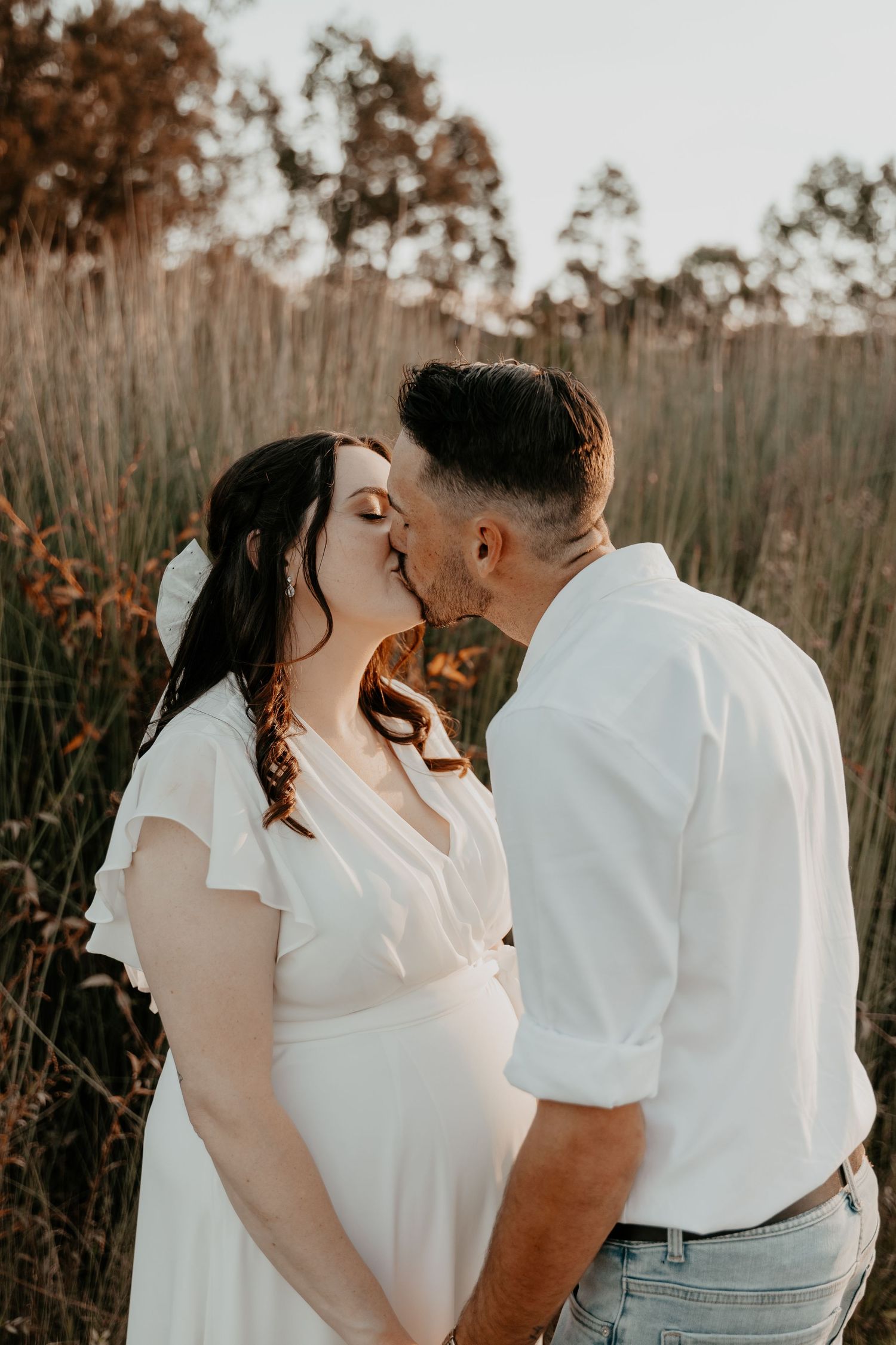 A newly wed couple kissing outside with the golden sun setting