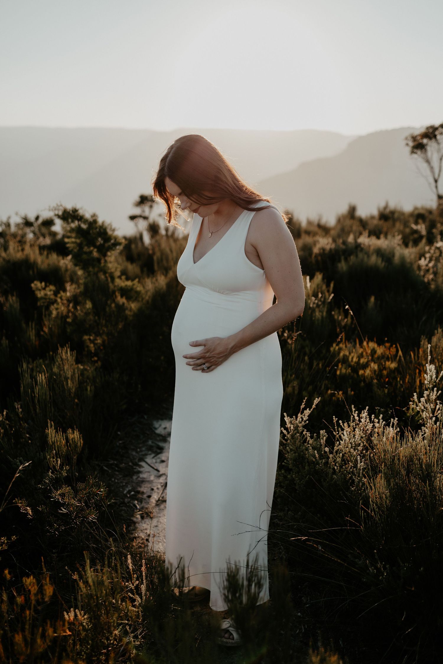 A Maternity photo of a women holding her belly during golden hour in the Blue Mountains