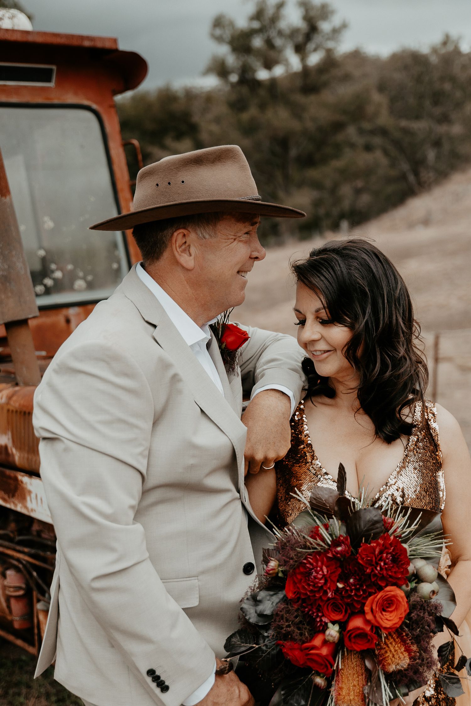 A country style wedding photo of the bride and groom near the tractor