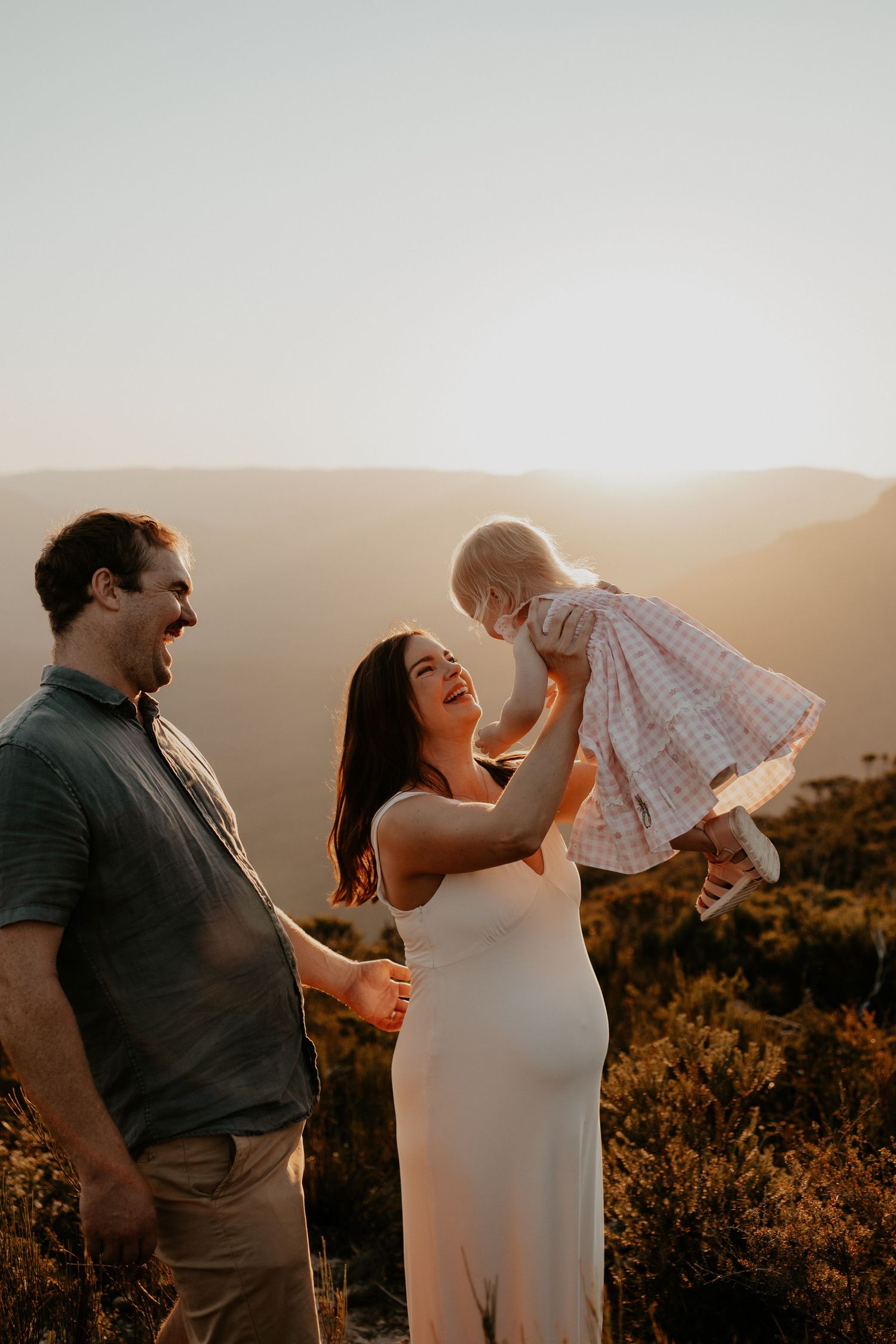 Creative golden light photo of a family of three with the back drop of the Blue Mountains escarpment as the sun is setting