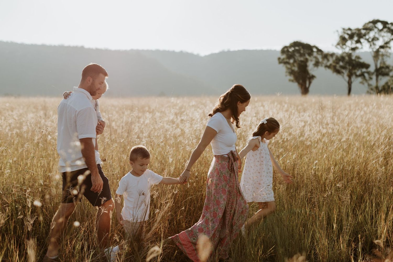 A family of 5 walking through golden fields in Penrith