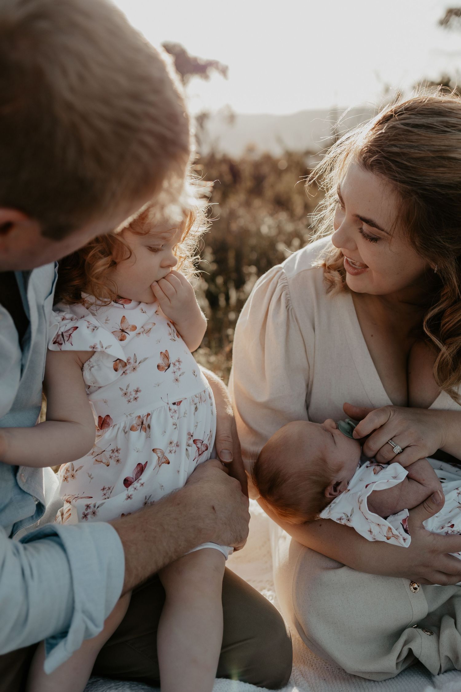 A family with a new baby interacting with her sibling in the golden light