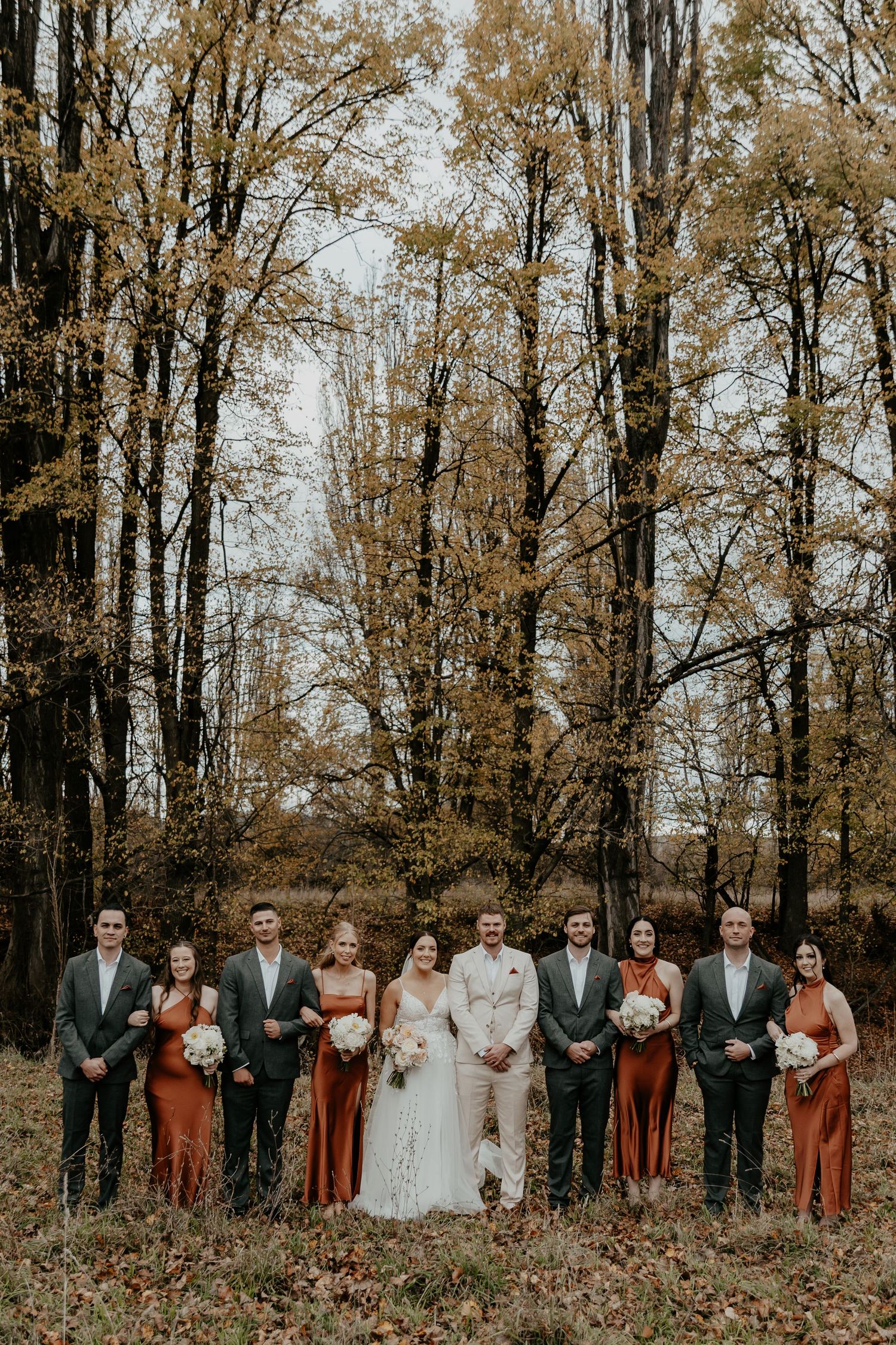 A bridal party standing in front of the Autumn leaves of the poplar trees