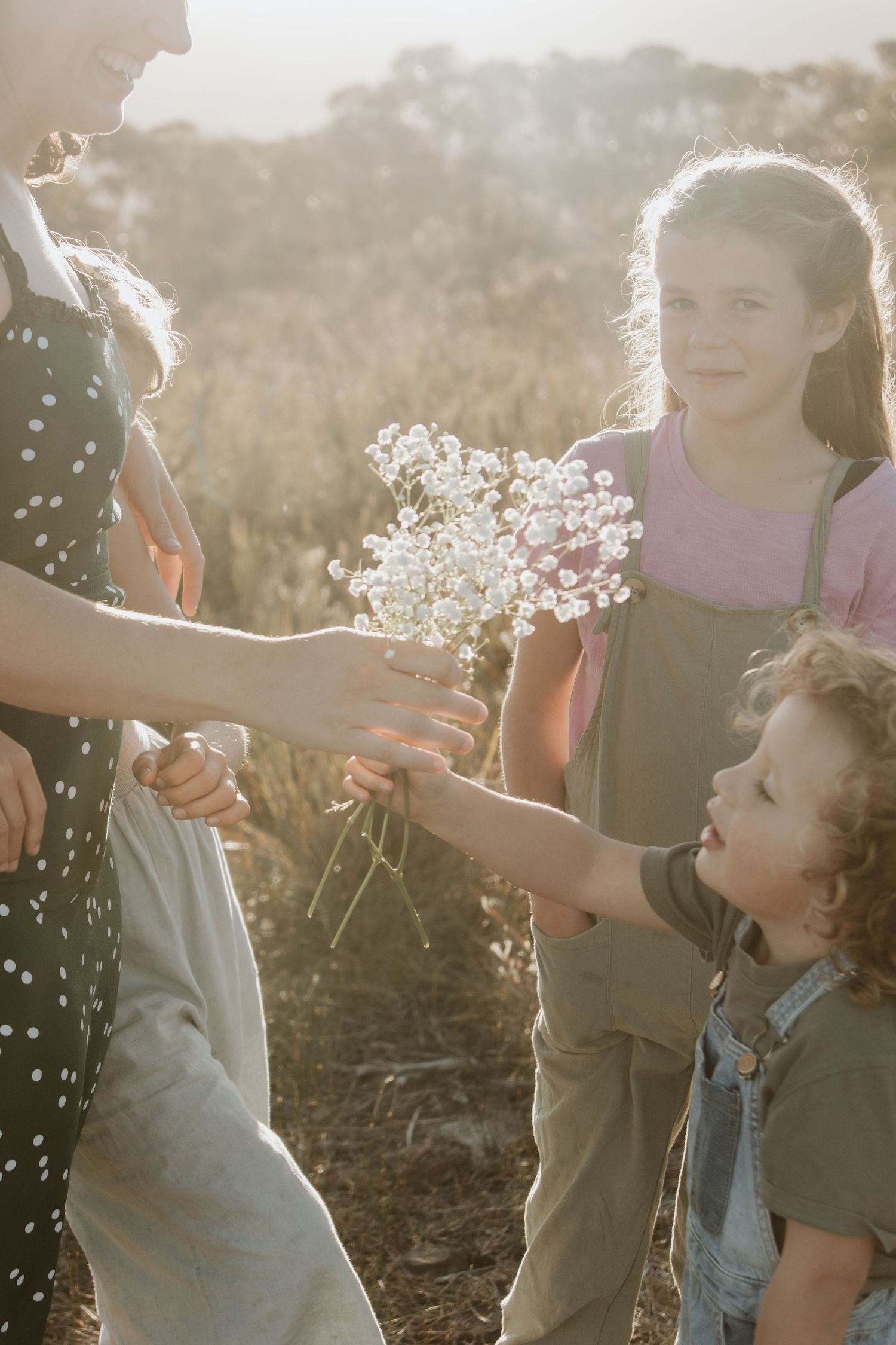 A Mothers Day photoshoot of the kids handing flowers to their mother at golden hour