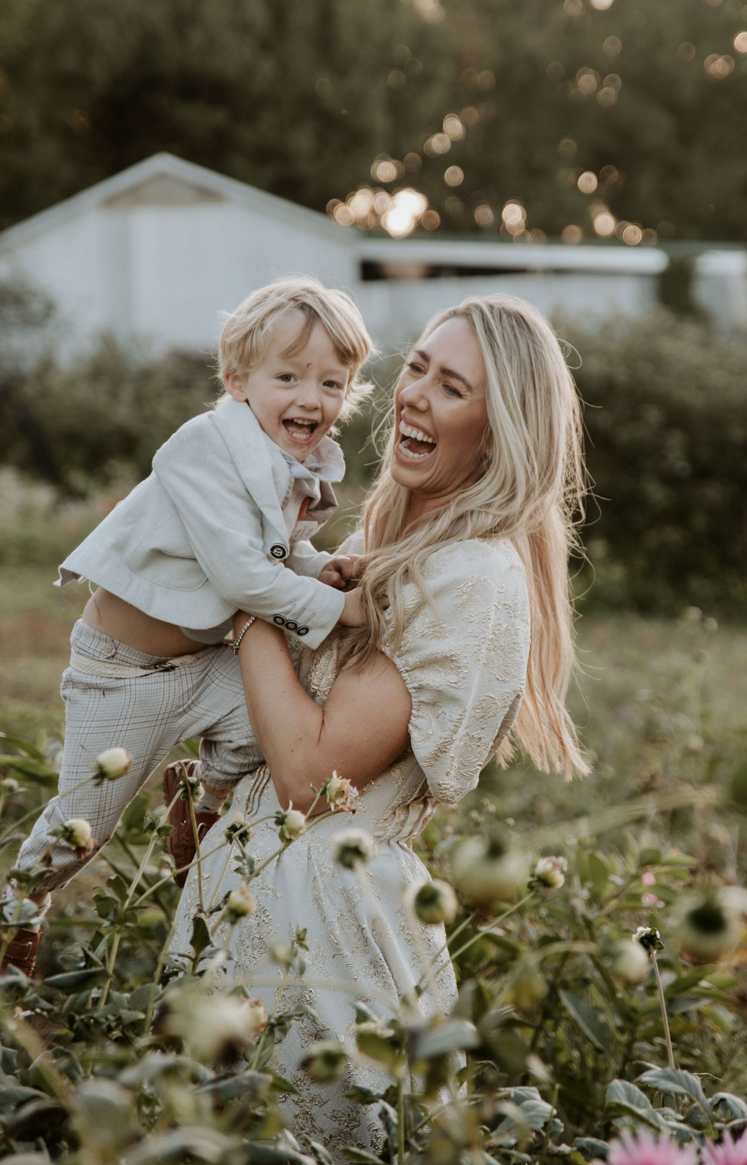 A mother lifting her child up in the flower fields whilst they both laugh in delight