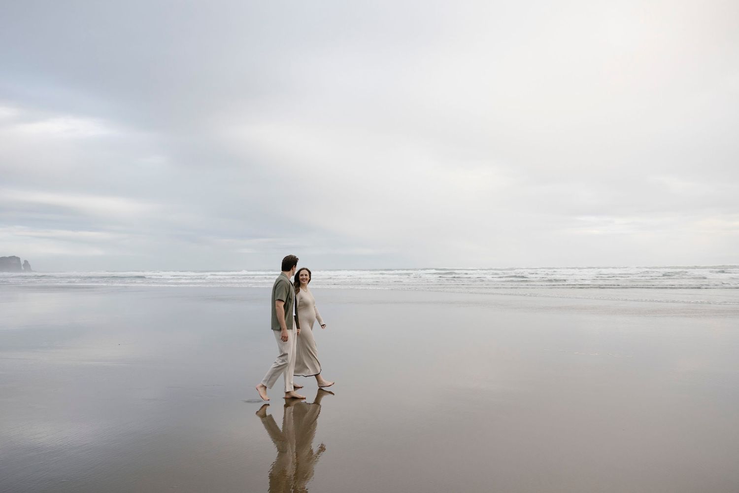 Maternity couple walking along the beach