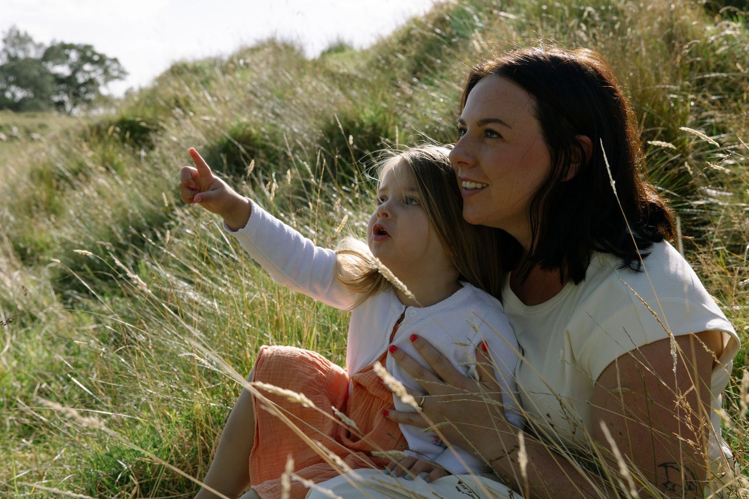 Little girl pointing to sky in mothers arms