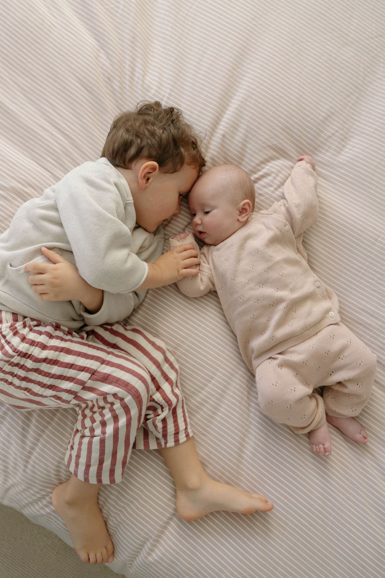 Brother and newborn sister lying on the bed