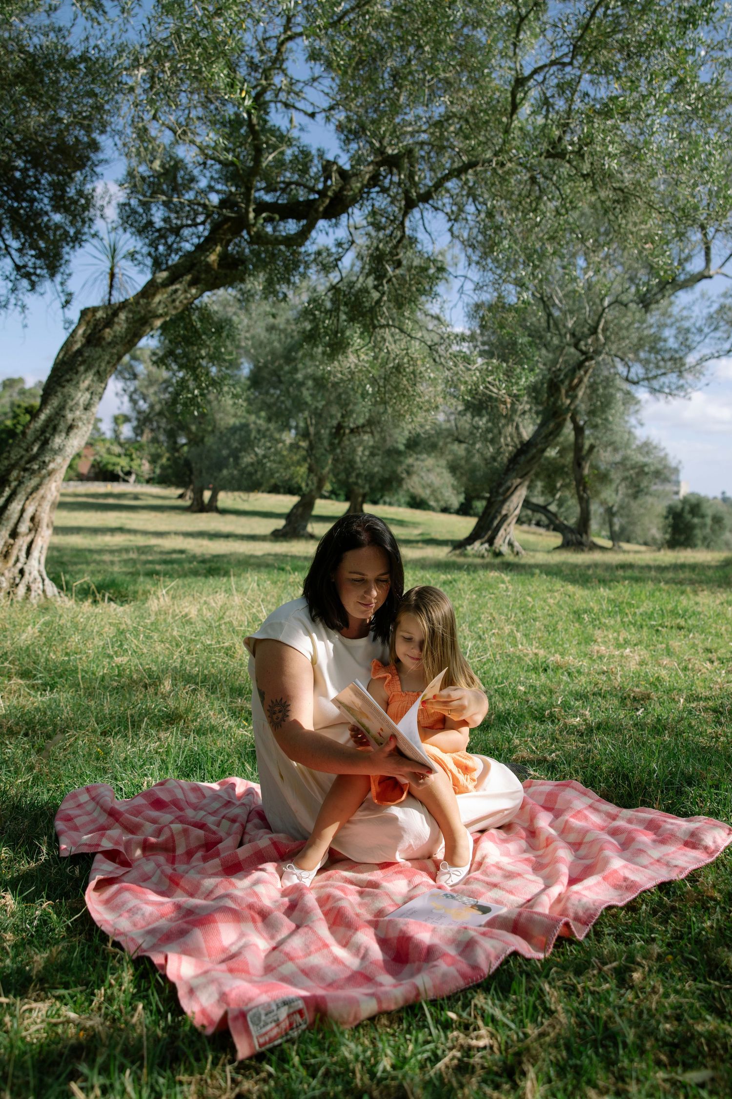 Mum and daughter reading under the trees
