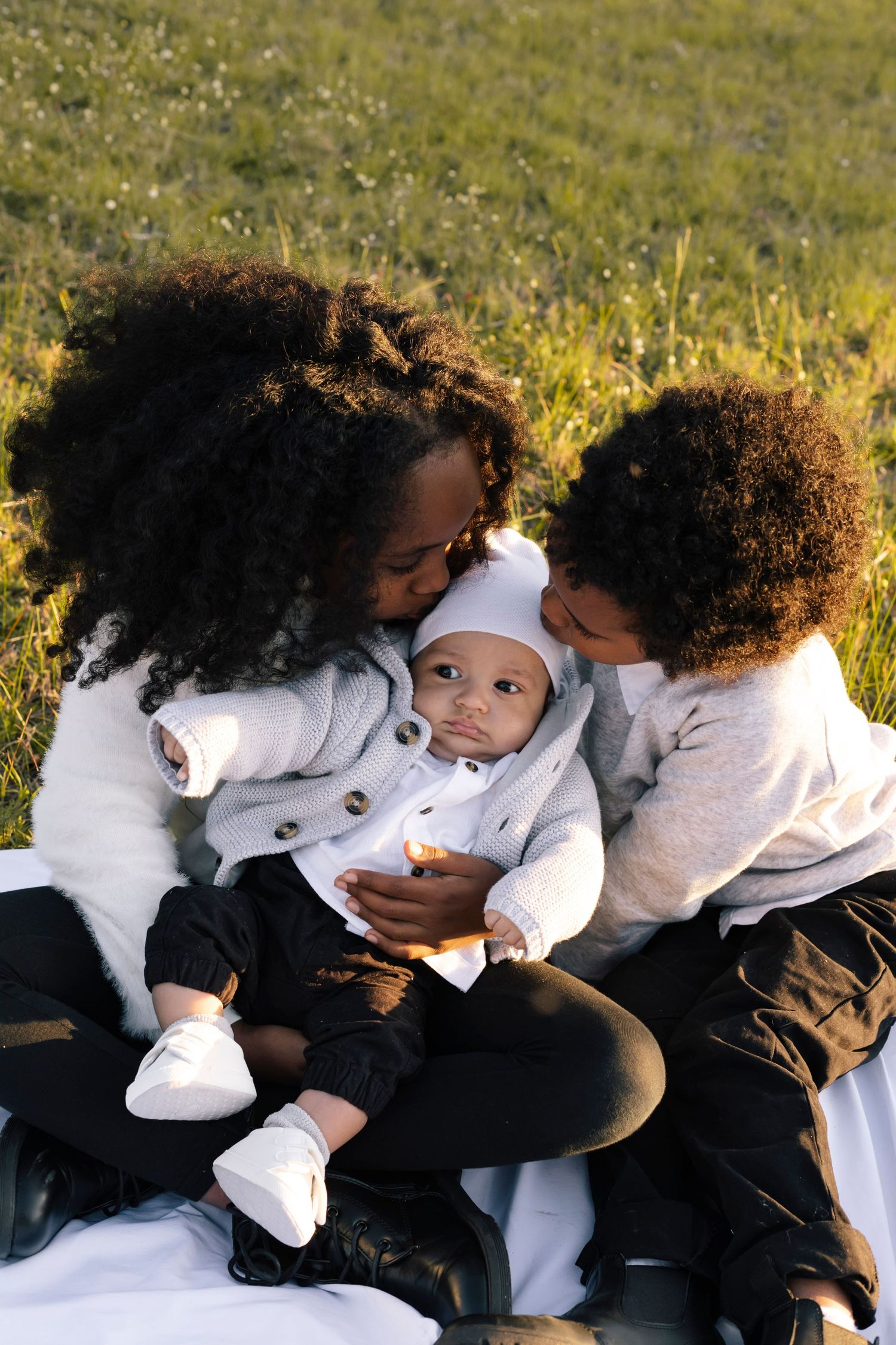 Brother and sister kissing their younger sibling