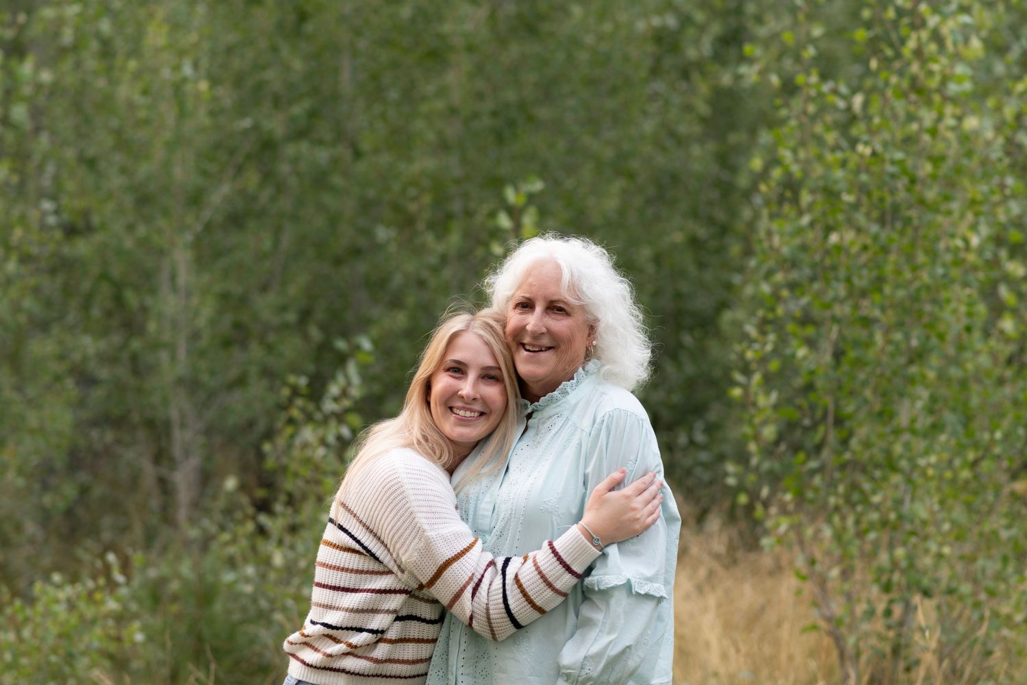 Couple embracing outdoors while enjoying nature on a sunny day in a grassy field.