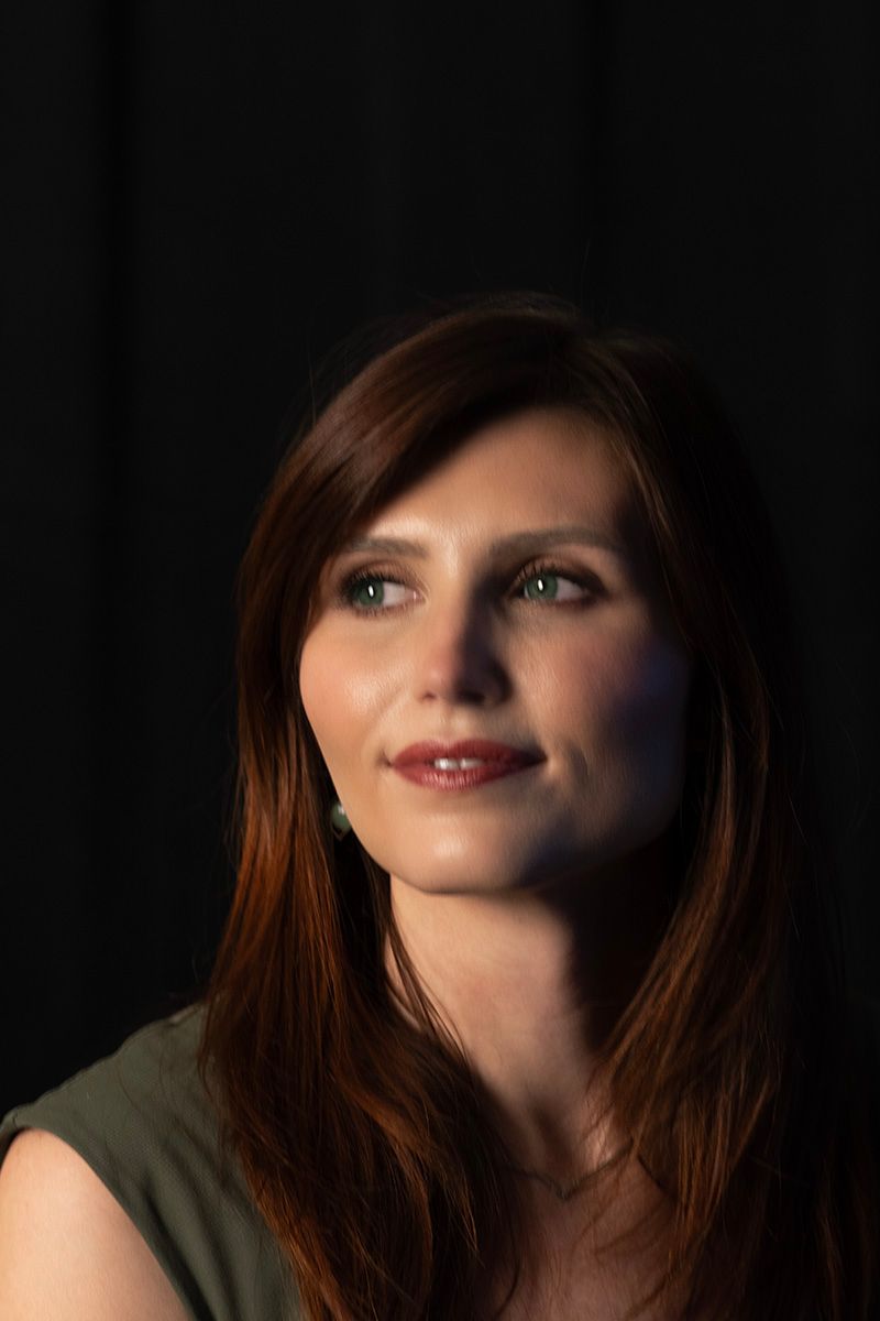 Artistic portrait with dramatic side lighting against dark background.