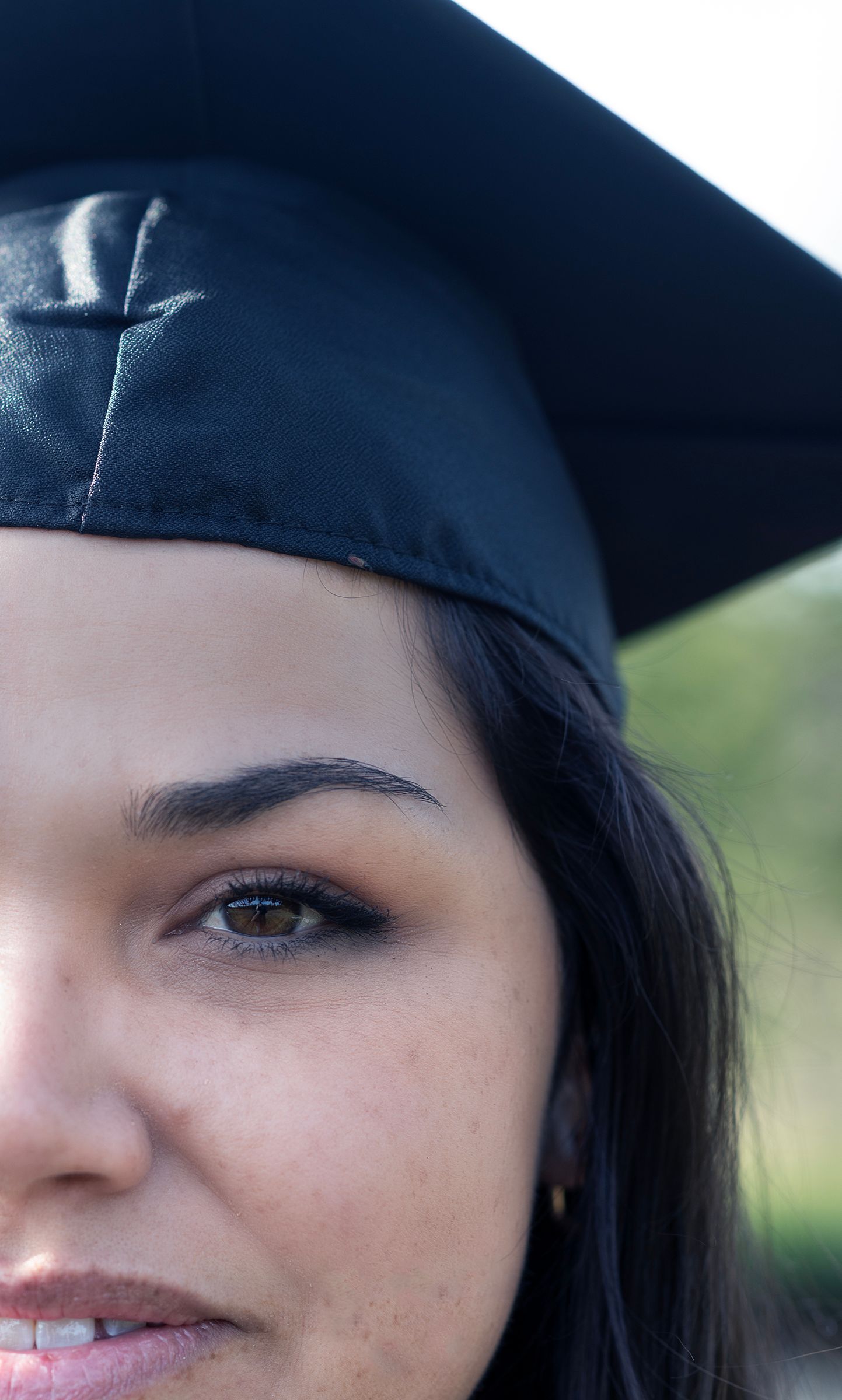Close-up portrait of a young woman wearing a black graduation cap, celebrating her academic achievement.