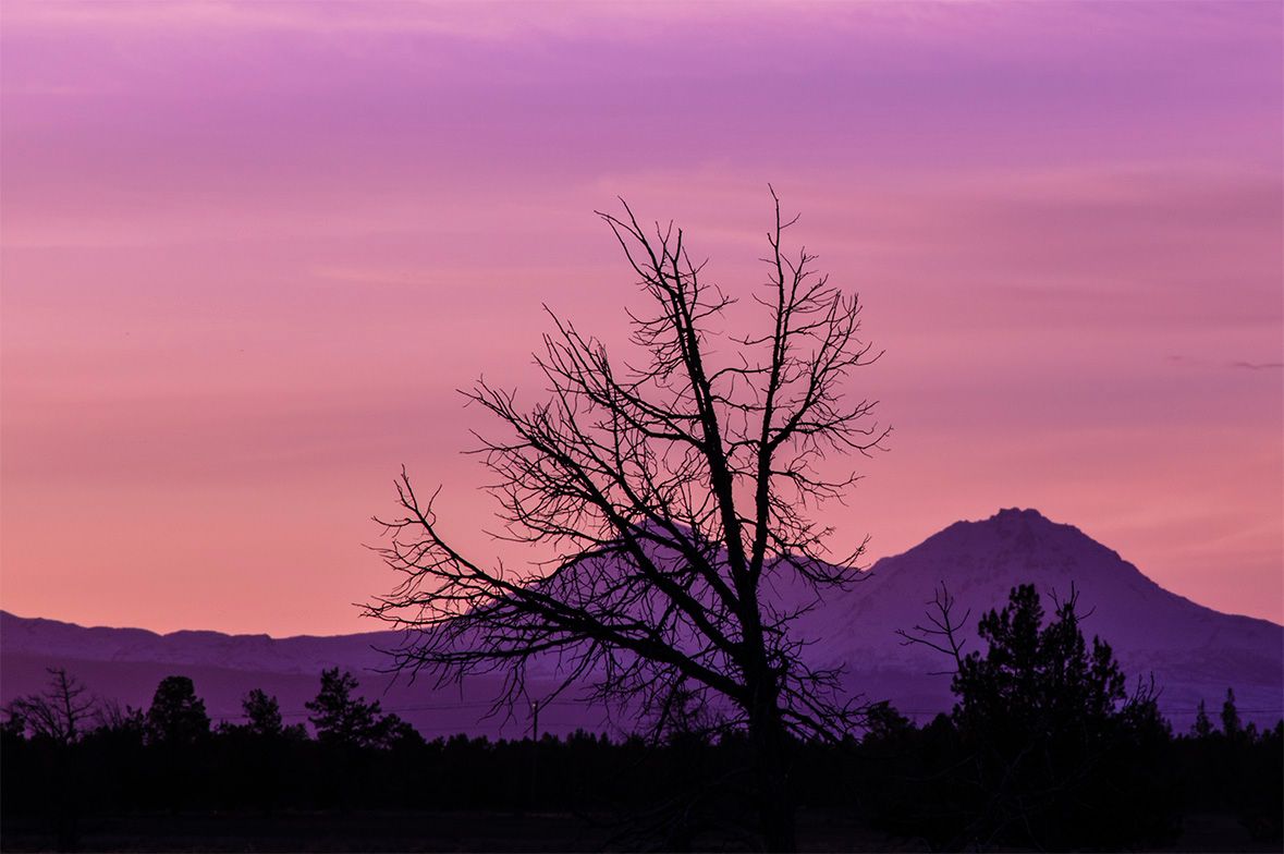 Mountain silhouettes against a vibrant purple and pink sunset sky.