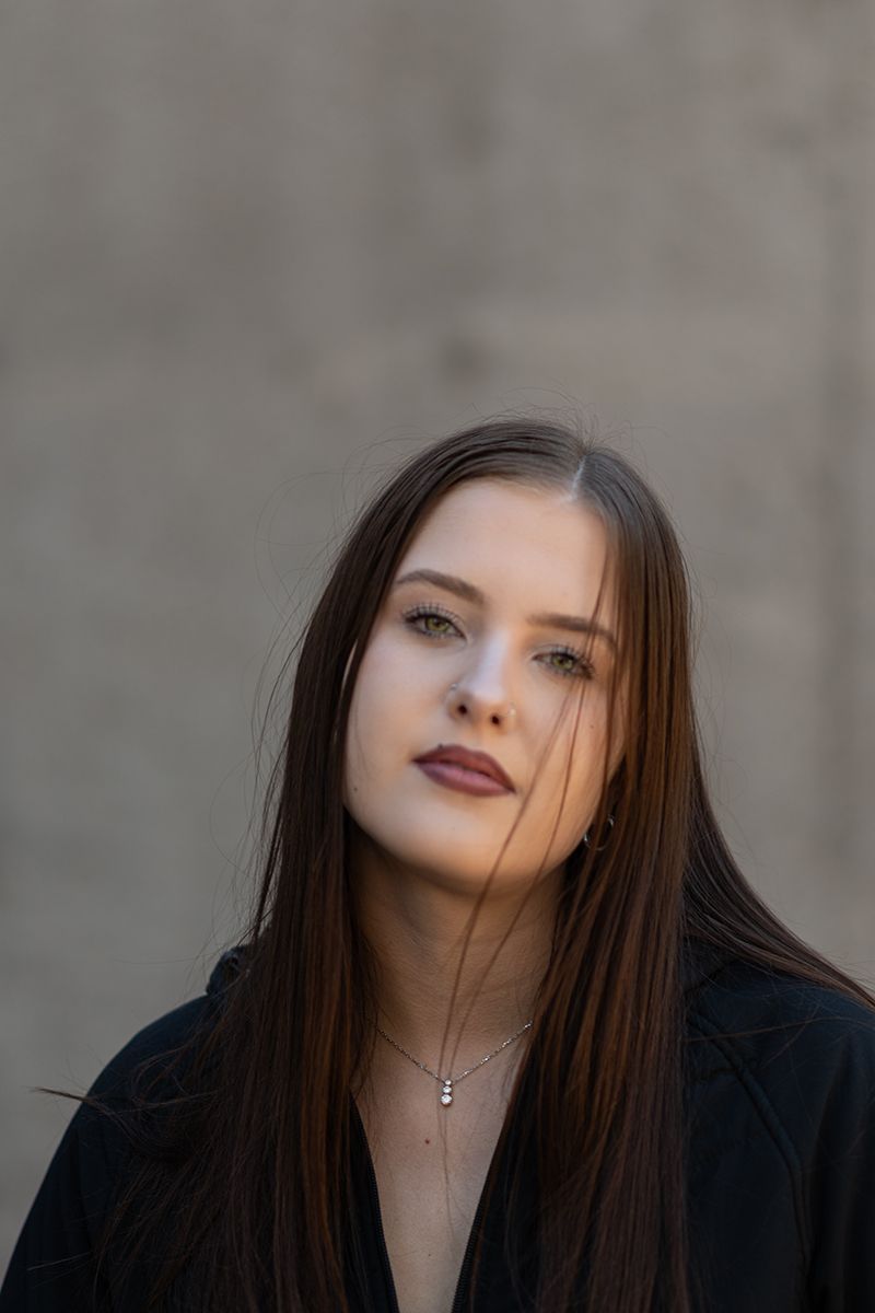 Artistic portrait series showing dark-haired woman in black clothing against gray wall with dramatic lighting and shadows.