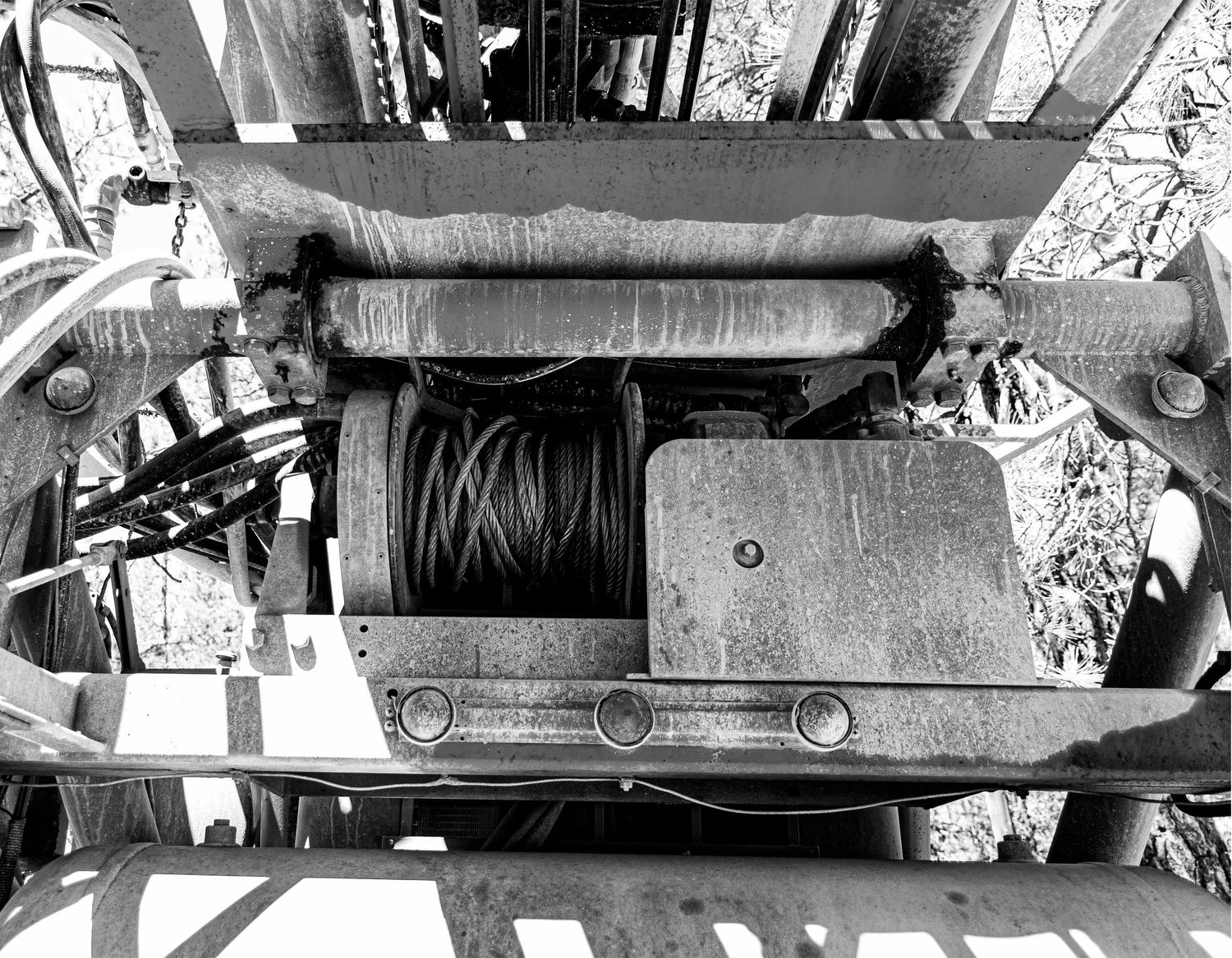 Industrial winch mechanism with steel cable spool mounted on heavy equipment.