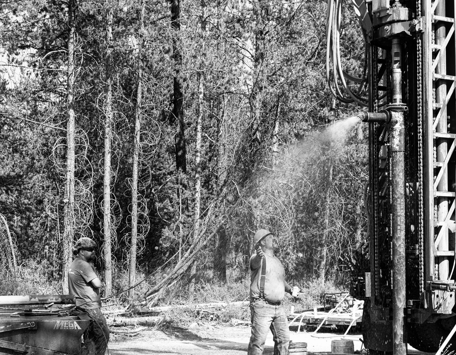 Heavy machinery and drilling equipment set up in a forest clearing.
