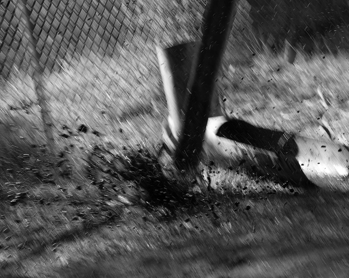 Dynamic black and white photo of a well drilling tool splashing on the soil with motion blur.