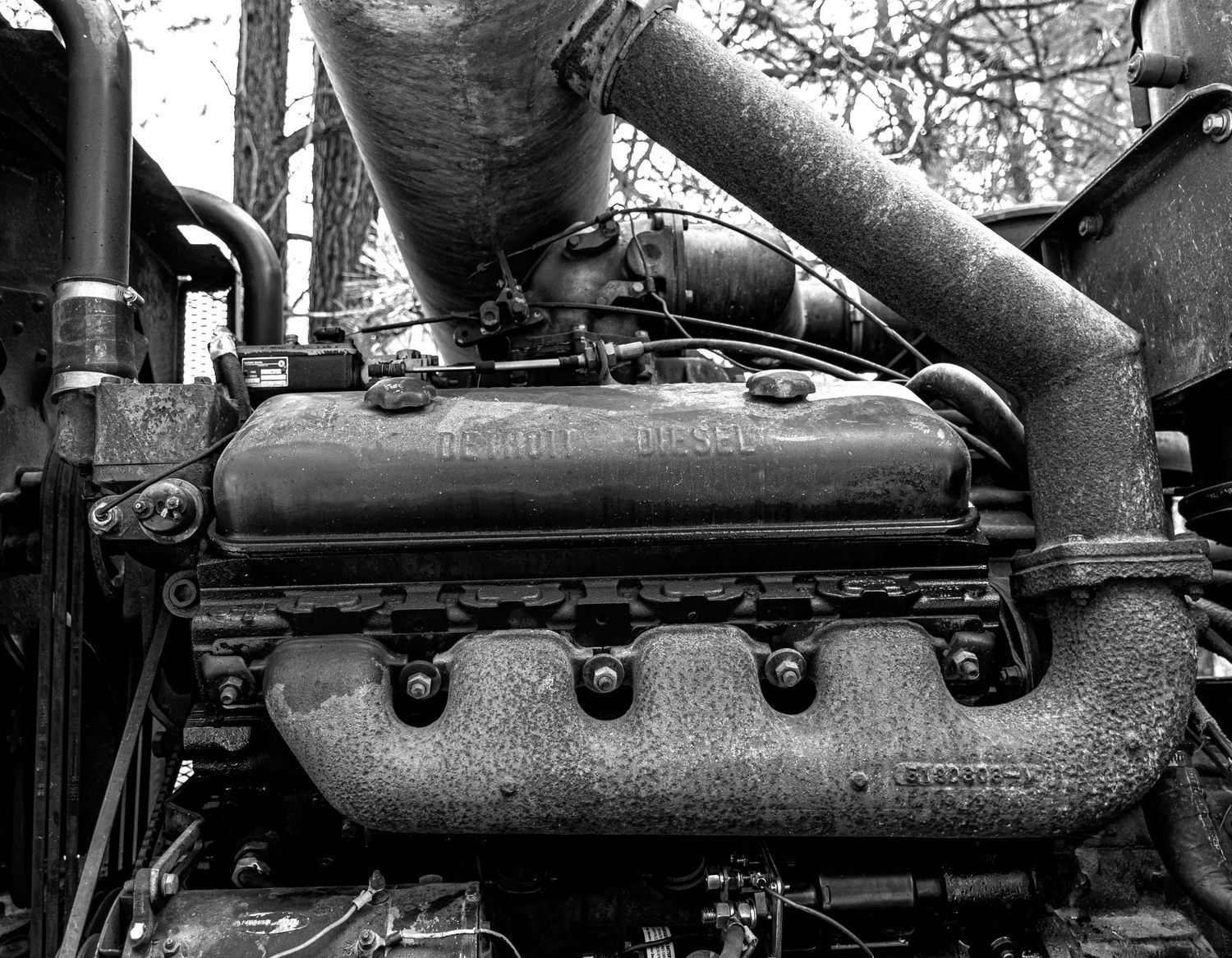 Detailed view of an old engine block with intake manifold and exhaust pipes.